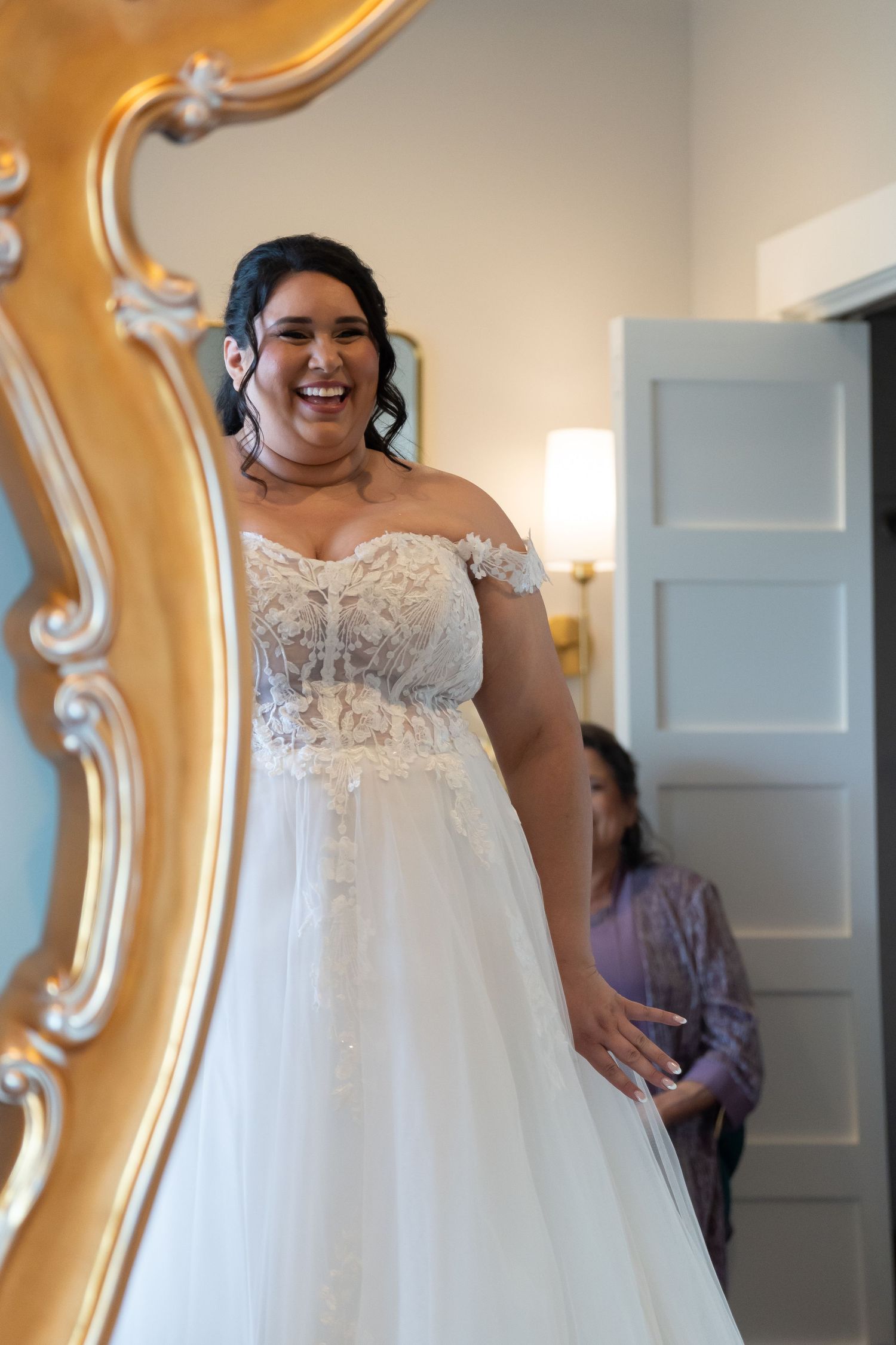 Wedding dress with delicate lace details and flowing tulle being displayed in a fitting room.