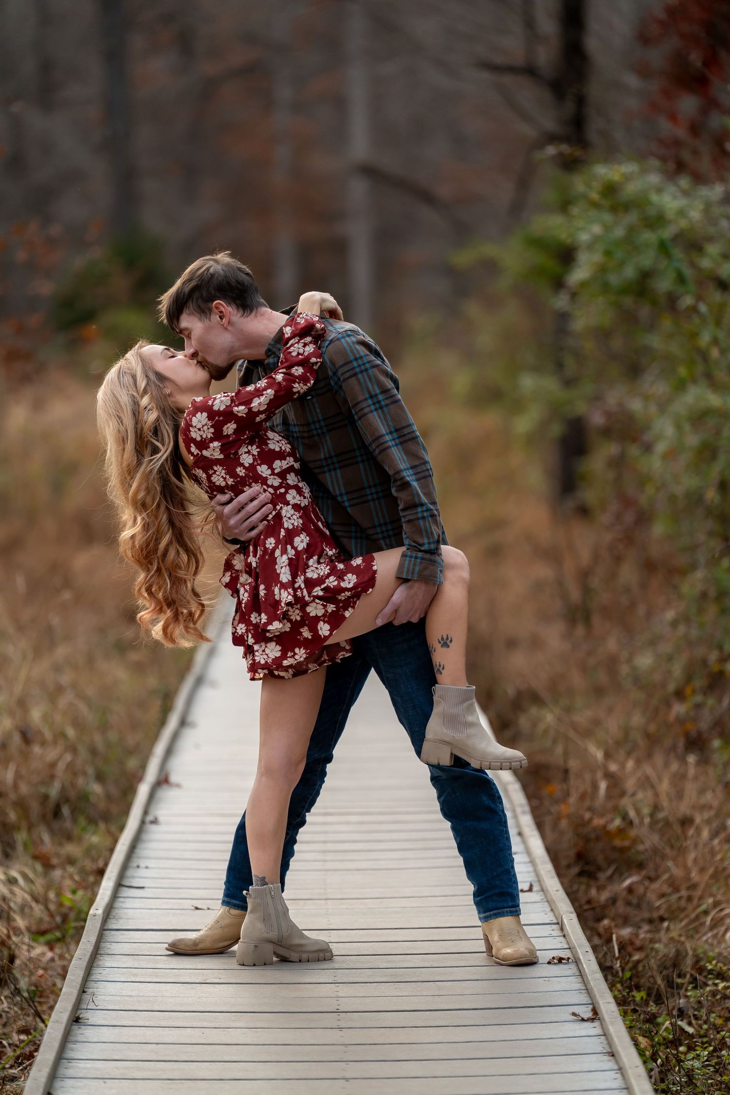 Romantic couple posing on wooden boardwalk during outdoor photoshoot.