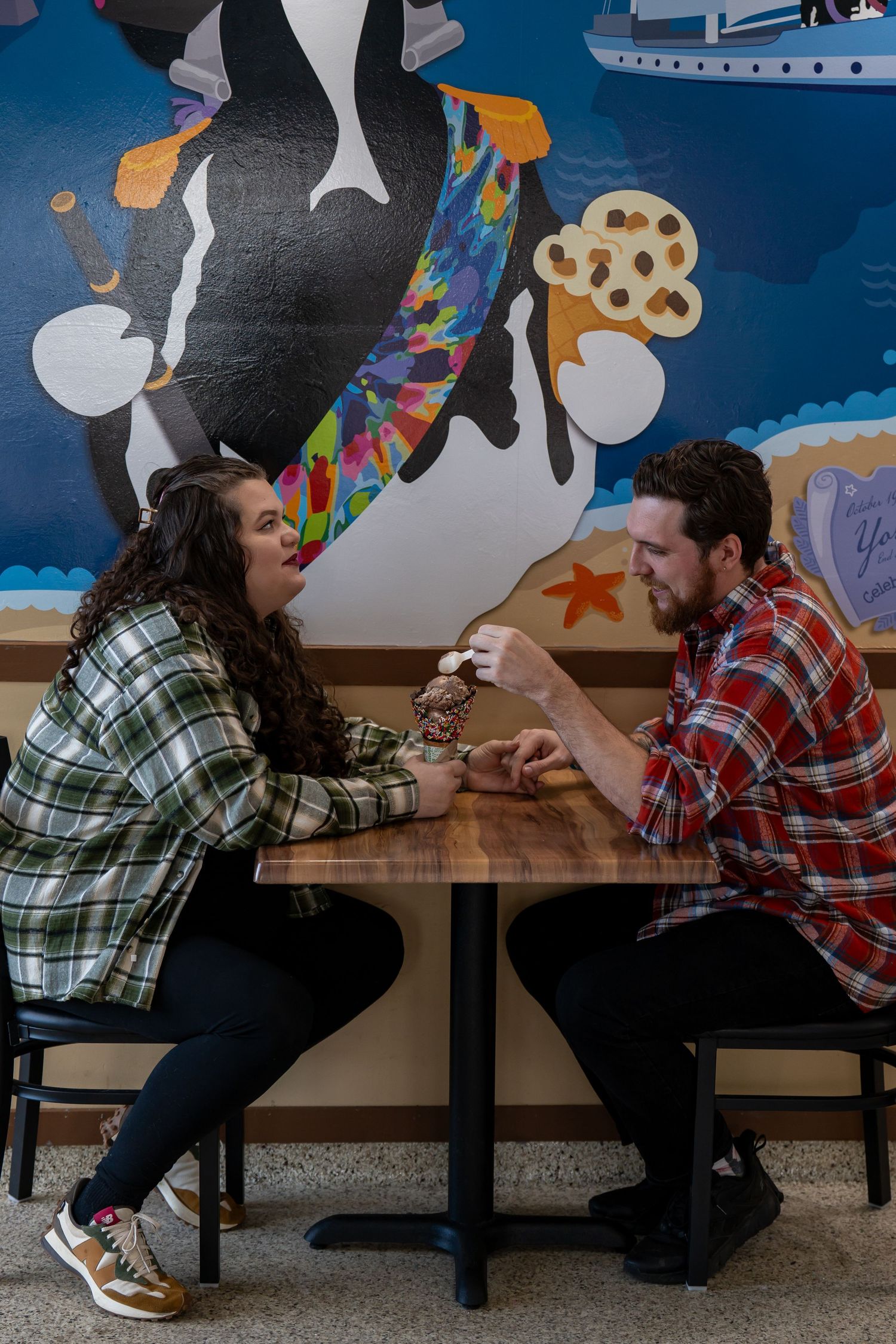 A couple in plaid shirts sharing a romantic moment at a restaurant booth.