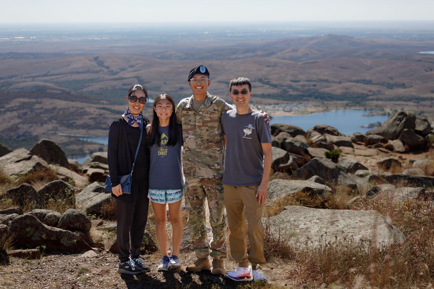 Group photo taken at scenic mountain overlook with rocky terrain in background.