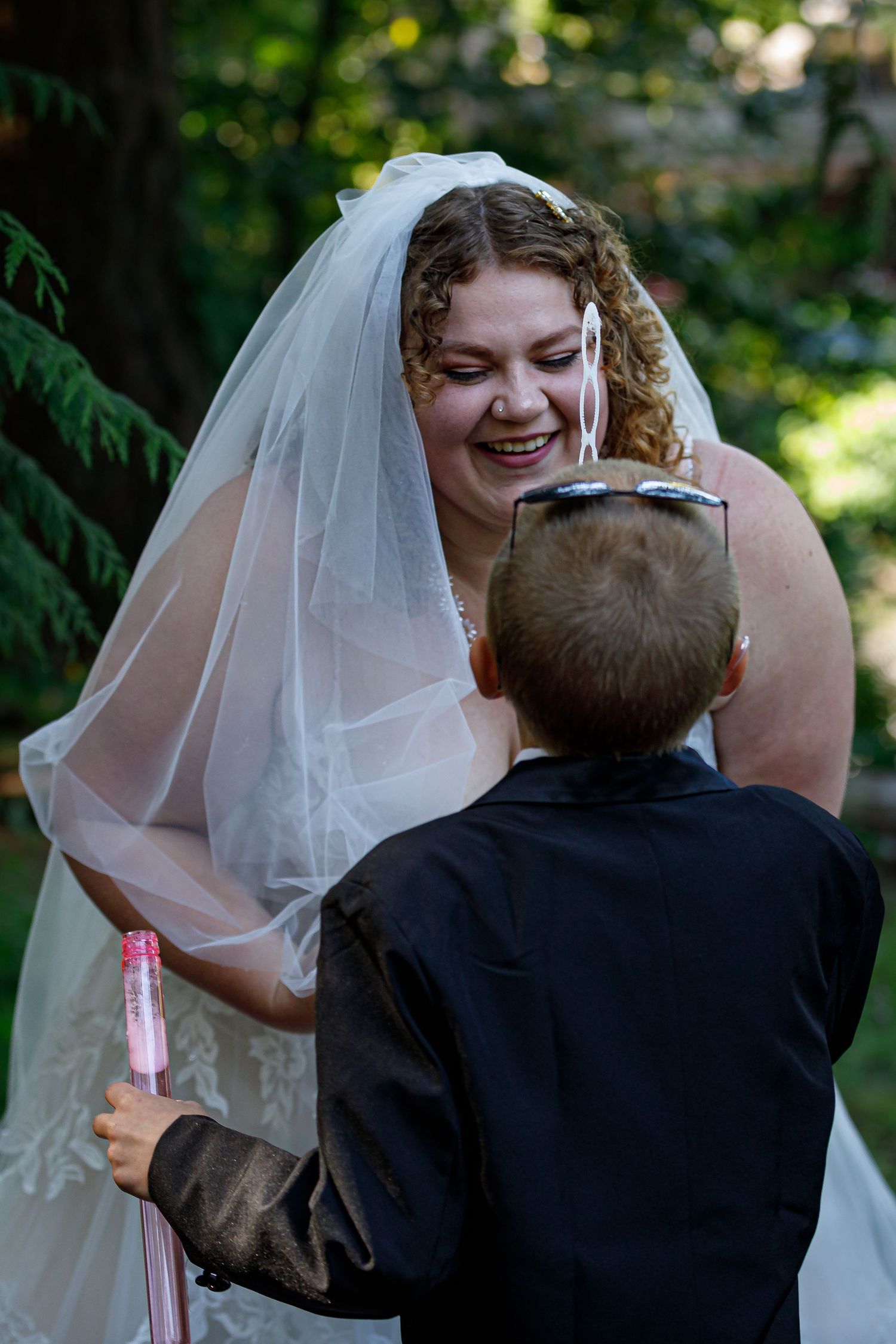 Heartwarming moment between bride and young ring bearer at outdoor wedding.