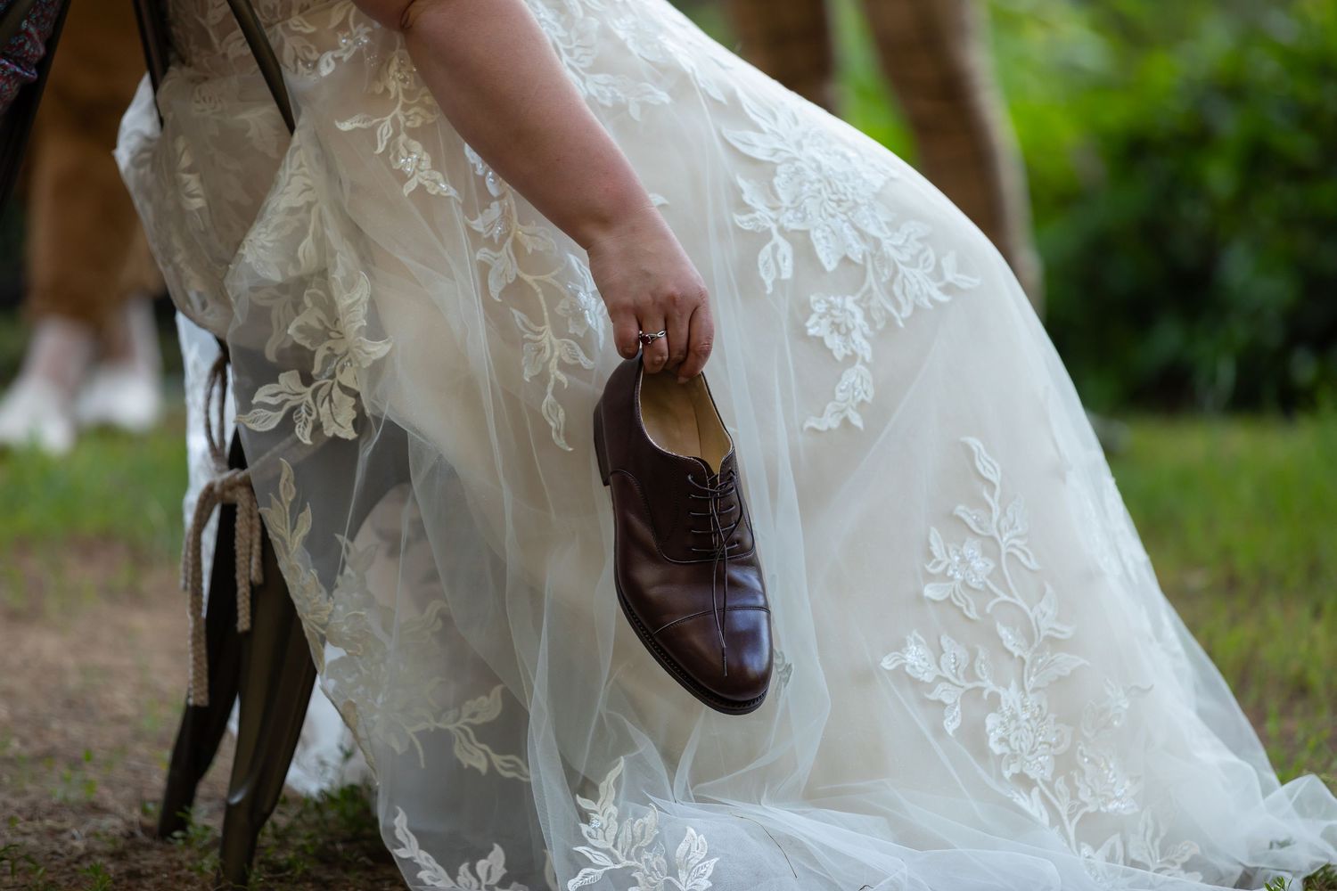 Elegant white wedding dress with lace detail shown in motion outdoors.