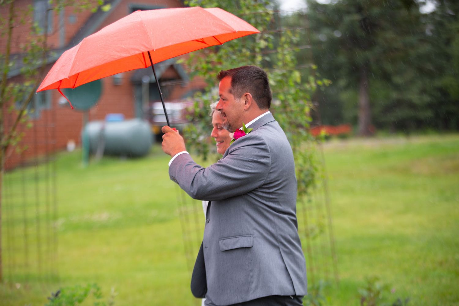 People with umbrellas gather on a rainy day in gray formal attire.
