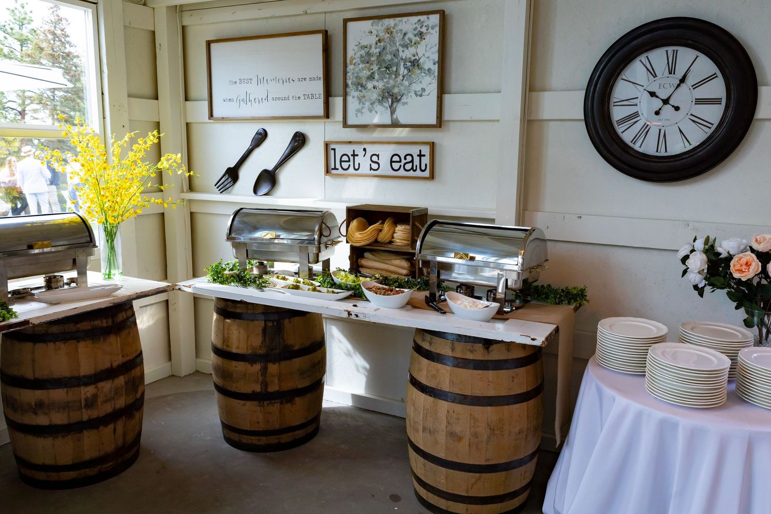 Rustic buffet setup with wooden barrels and white serving dishes.