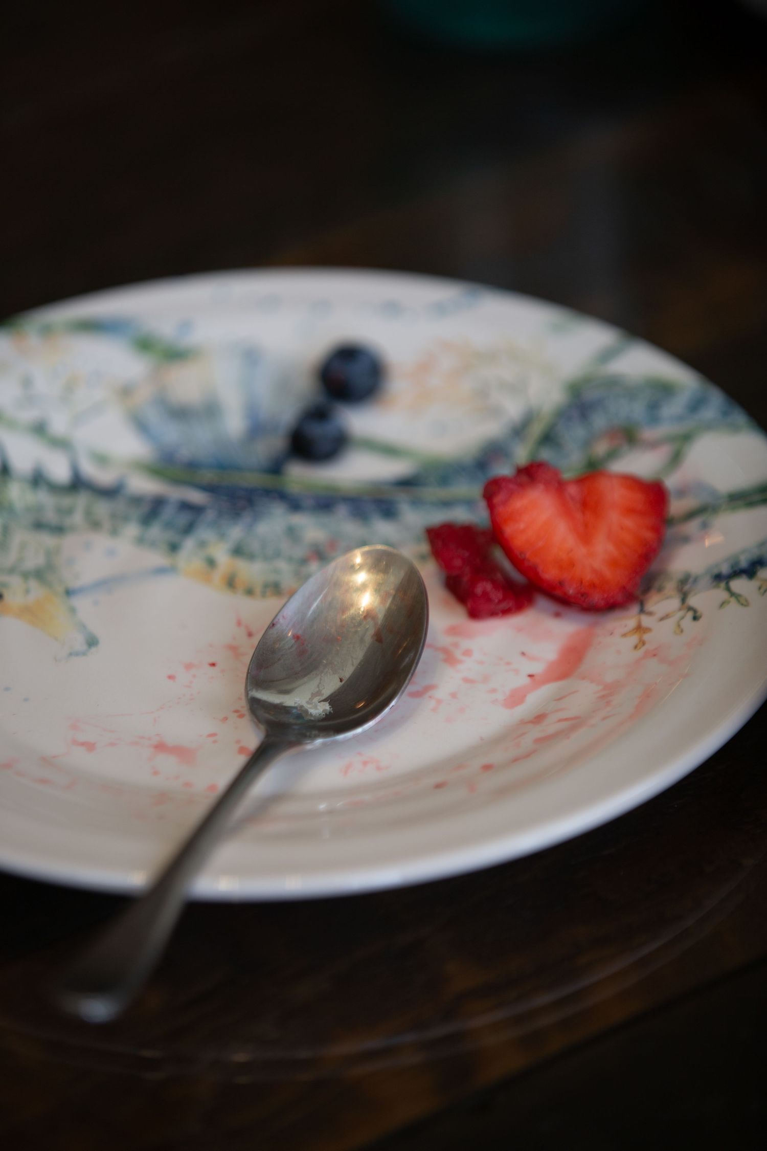 Empty dessert plates with remnants of strawberries and red stains showcase a finished sweet treat.