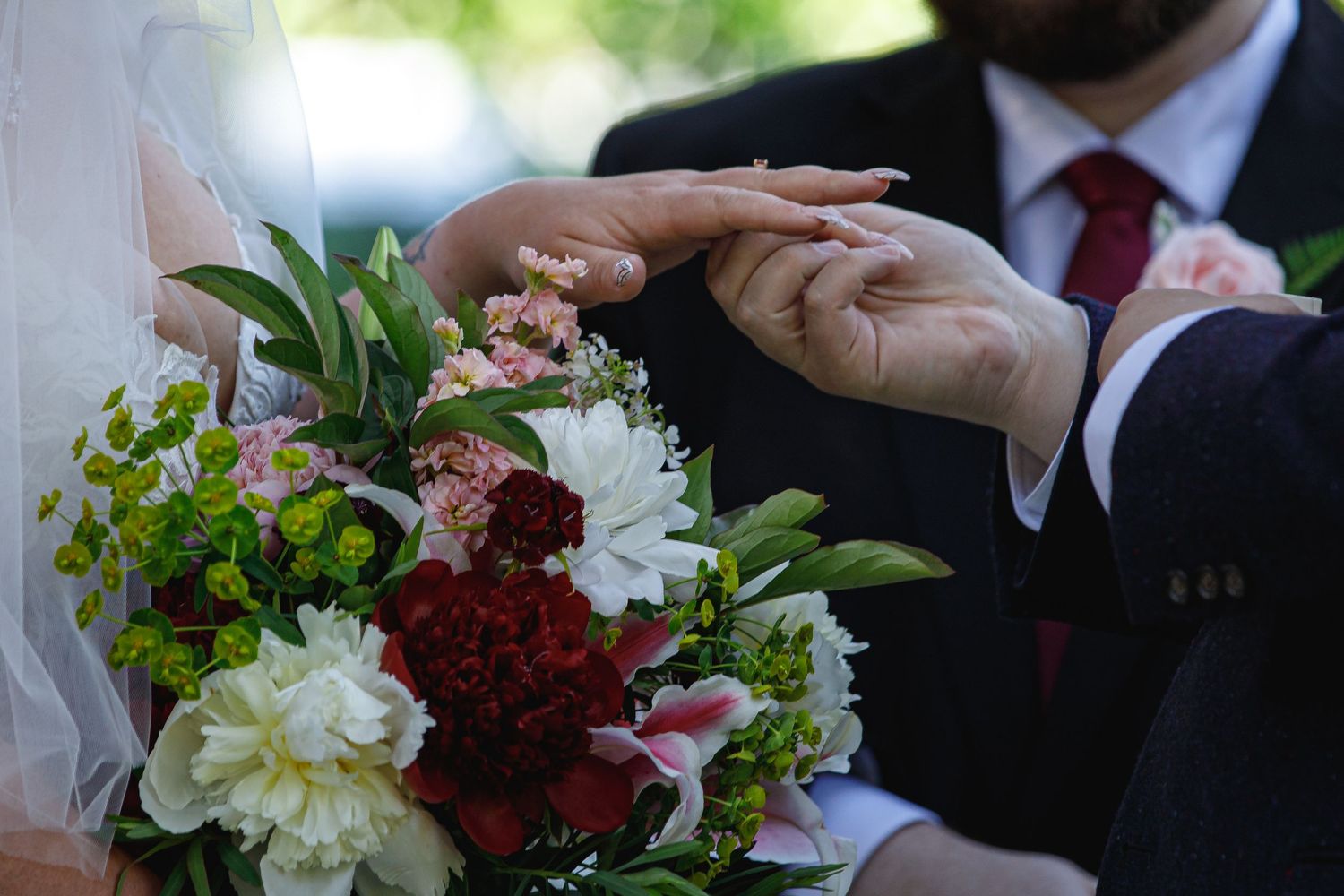 Wedding bouquets with deep red and white flowers displayed at an outdoor ceremony.