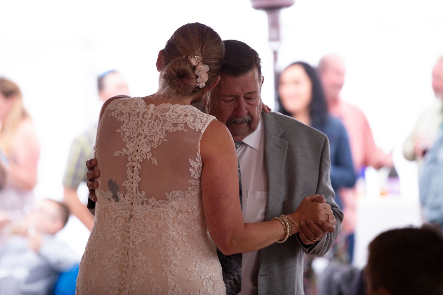 A couple shares their first dance at a wedding reception under soft lighting.