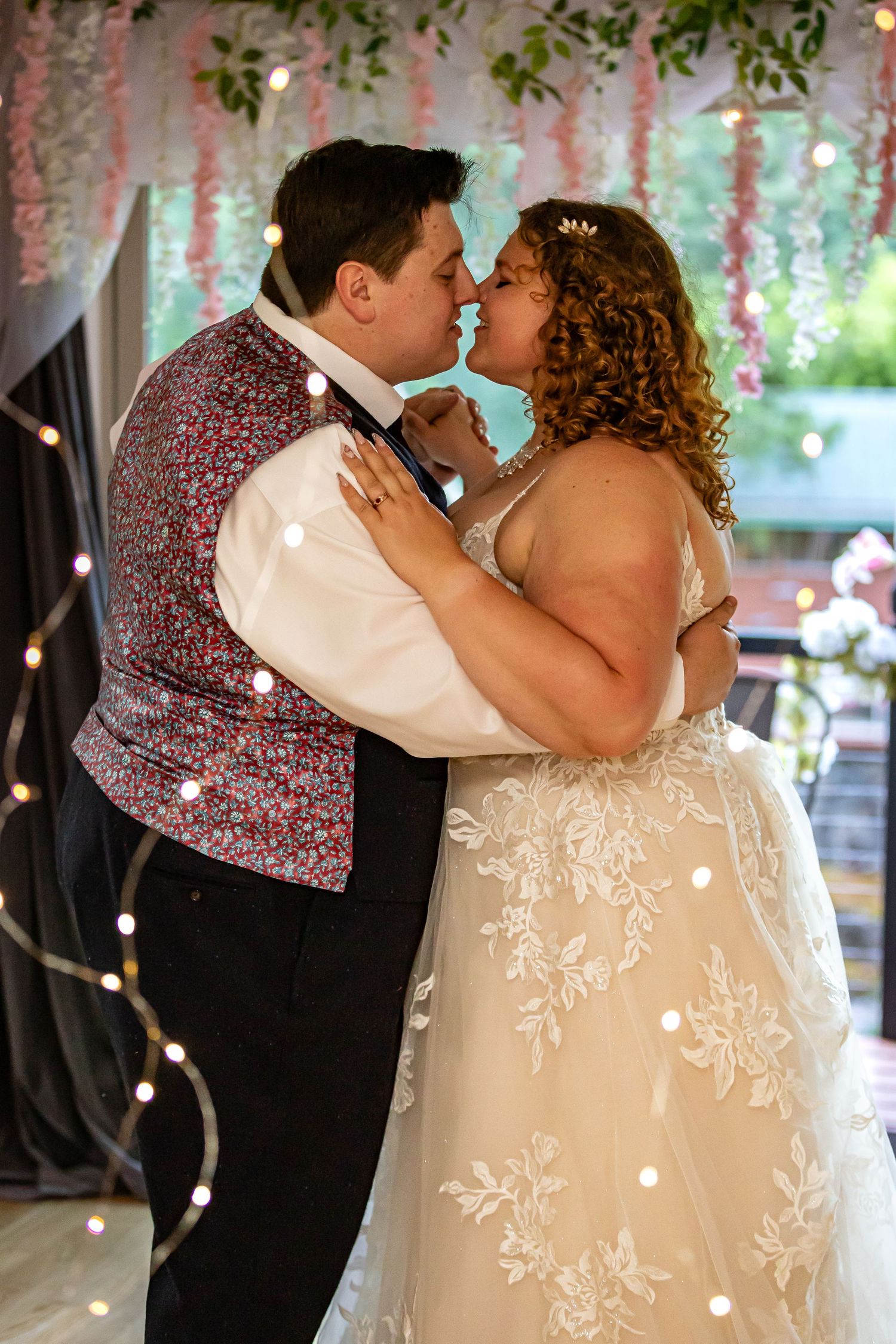 A couple sharing a romantic dance moment under twinkle lights at their wedding reception.