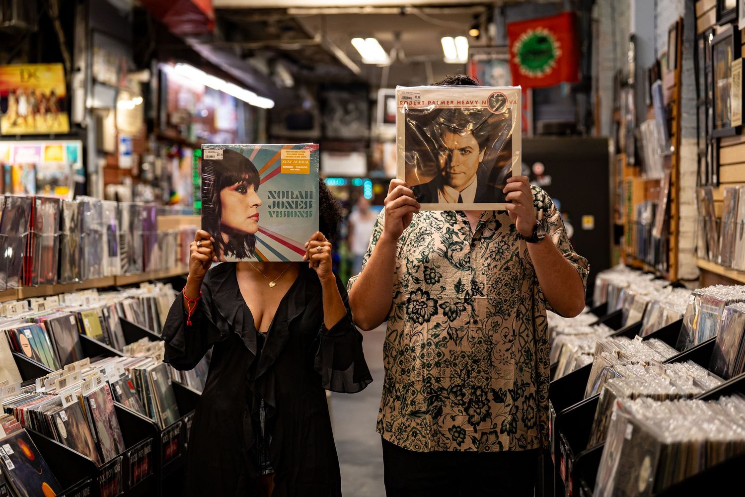 Two people browsing vinyl records in a music store with colorful displays and album covers.