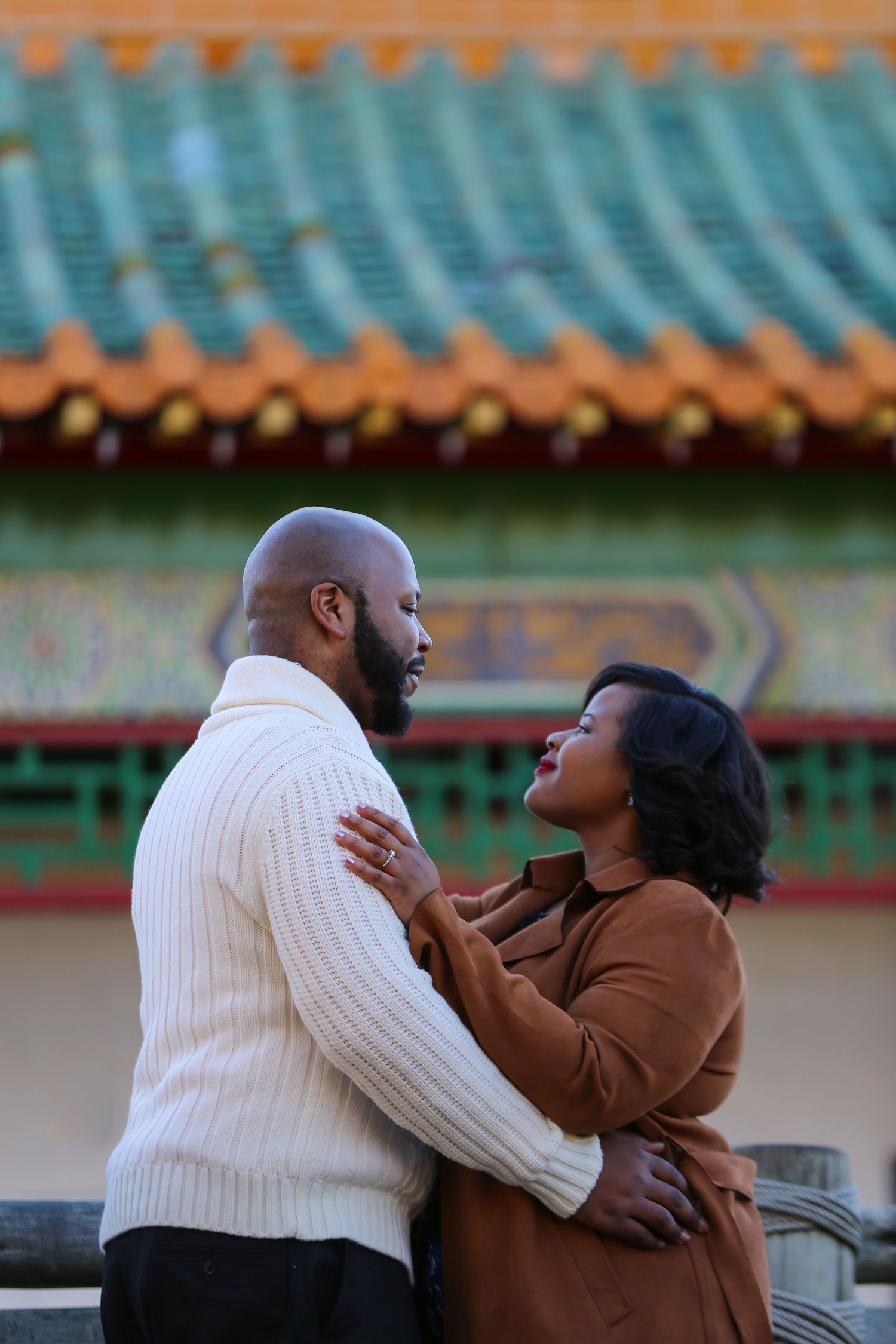 Romantic black couple embracing against traditional Asian architecture with teal roof tiles at the Japanese Pagoda in Norfolk, Virginia.