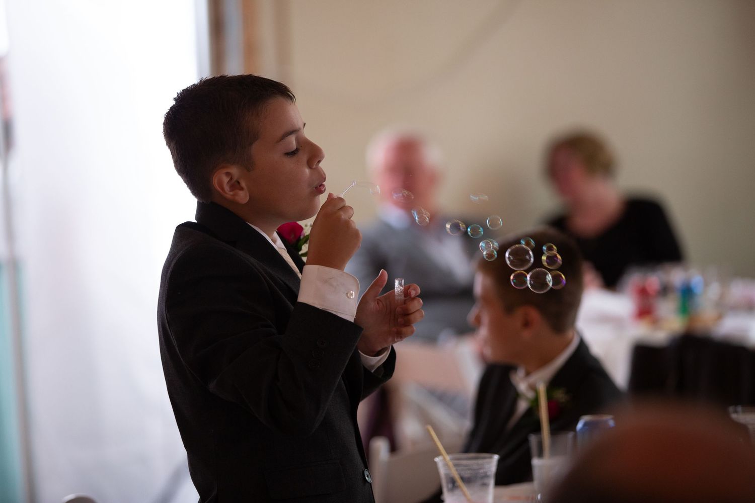 Wedding guests in formal attire sitting at a reception table indoors.
