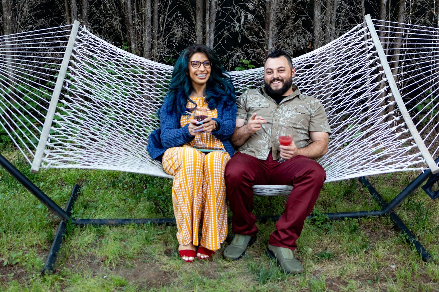 A white hammock stretches between trees in a wooded outdoor setting.