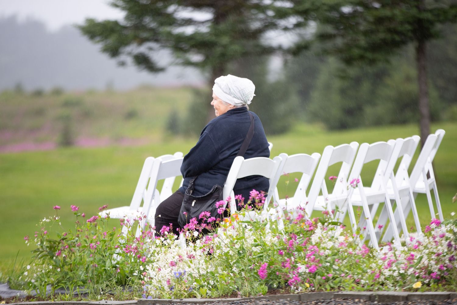 White chairs arranged outdoors with pink flowers in a garden setting.