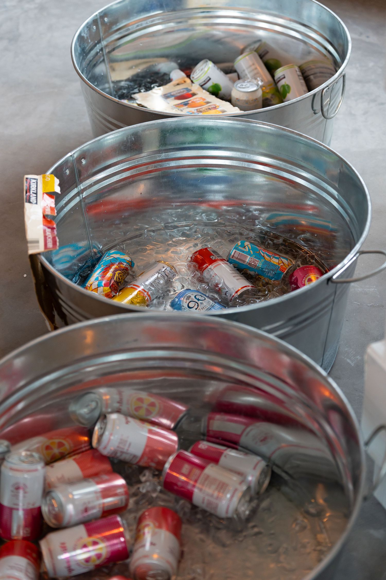 Metal tubs filled with assorted beverages on ice at an event.