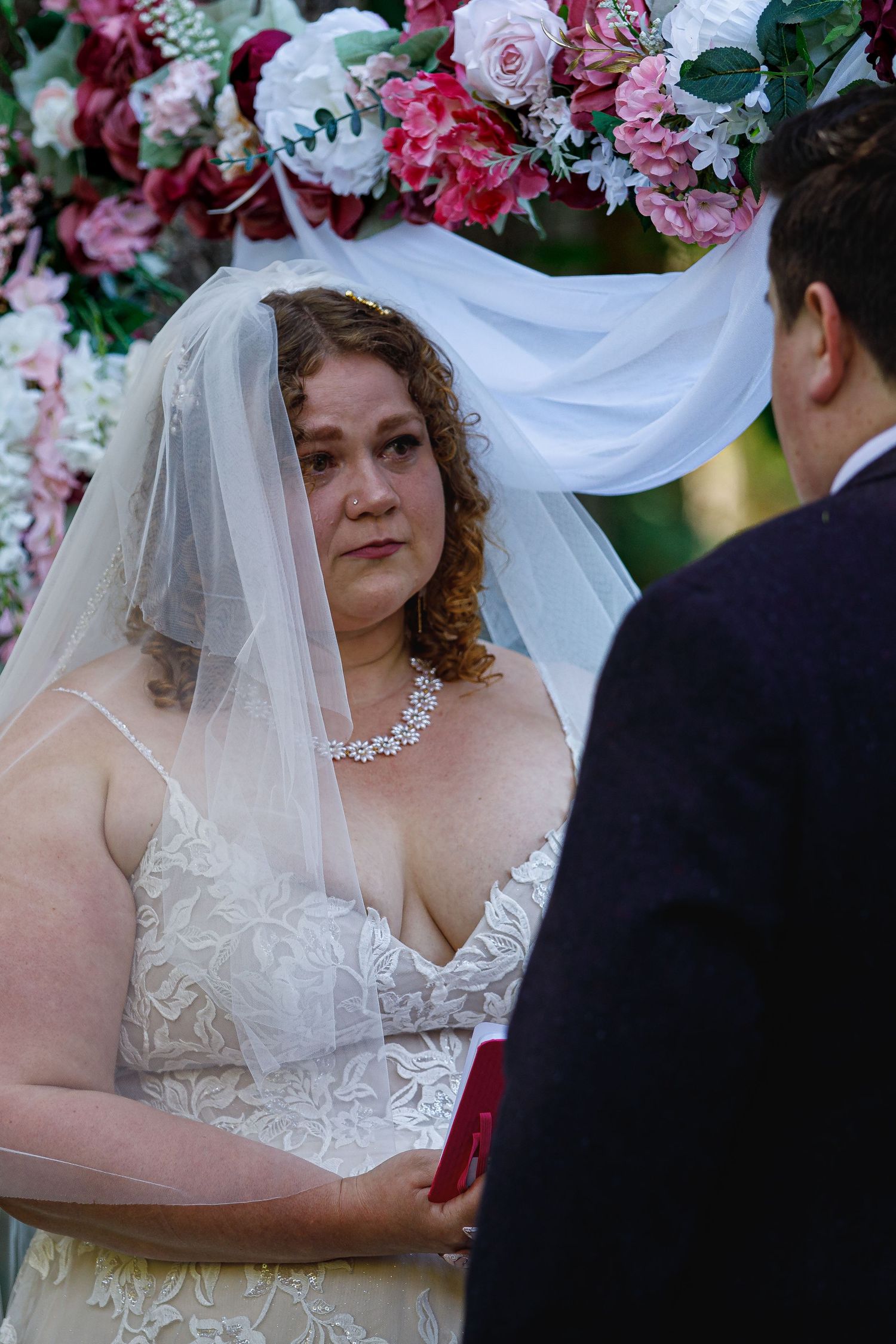 Wedding ceremony exchange with pink and white floral arch decorations.
