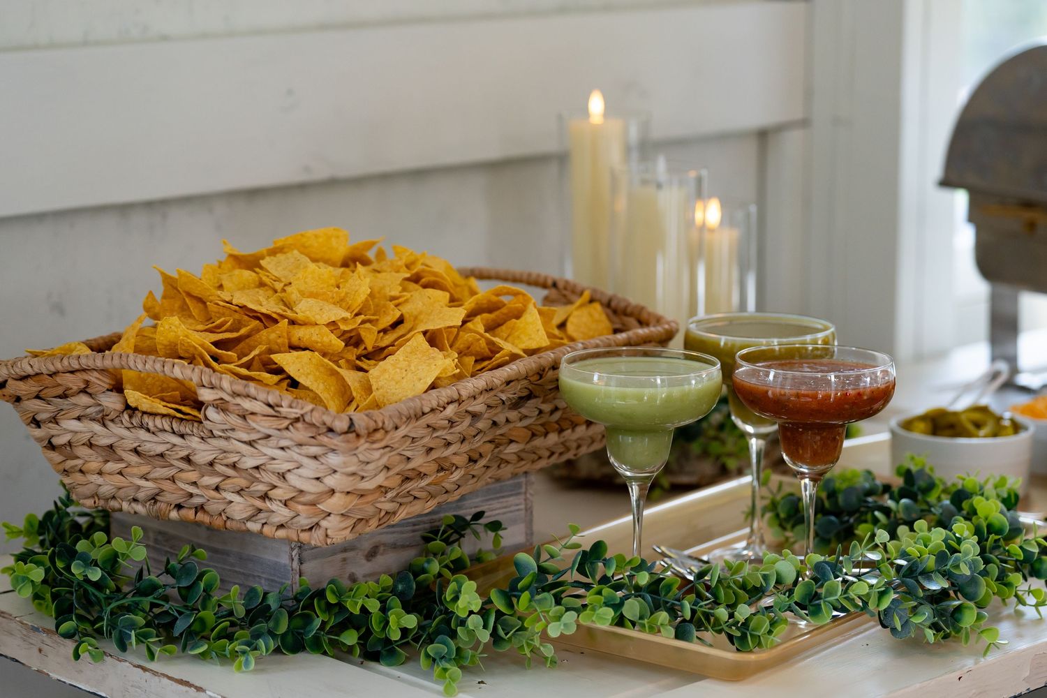 Appetizer station with tortilla chips, dips and garnishes arranged on rustic display.