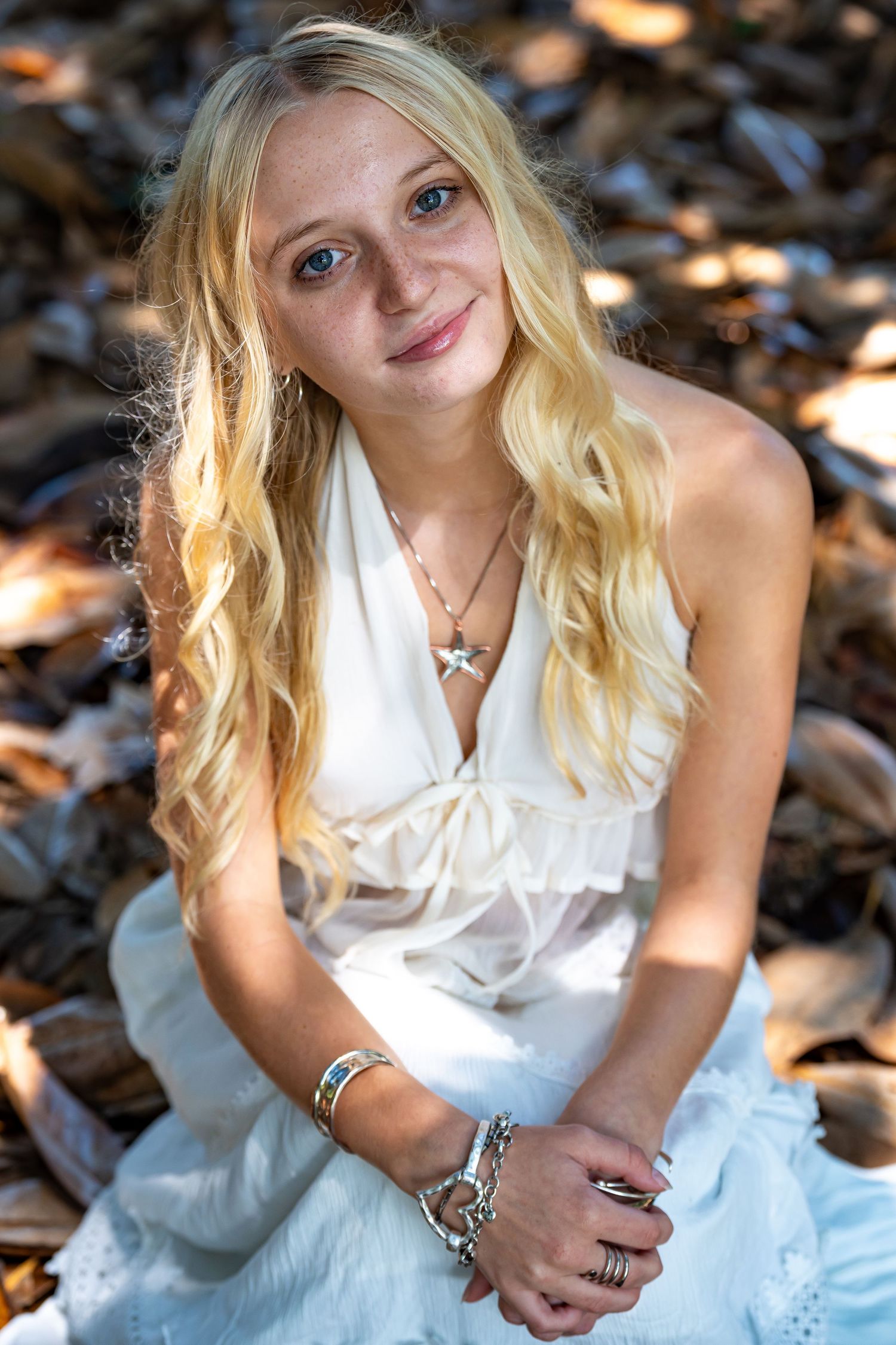A series of outdoor portrait shots showing a person in a white dress sitting among fallen leaves.