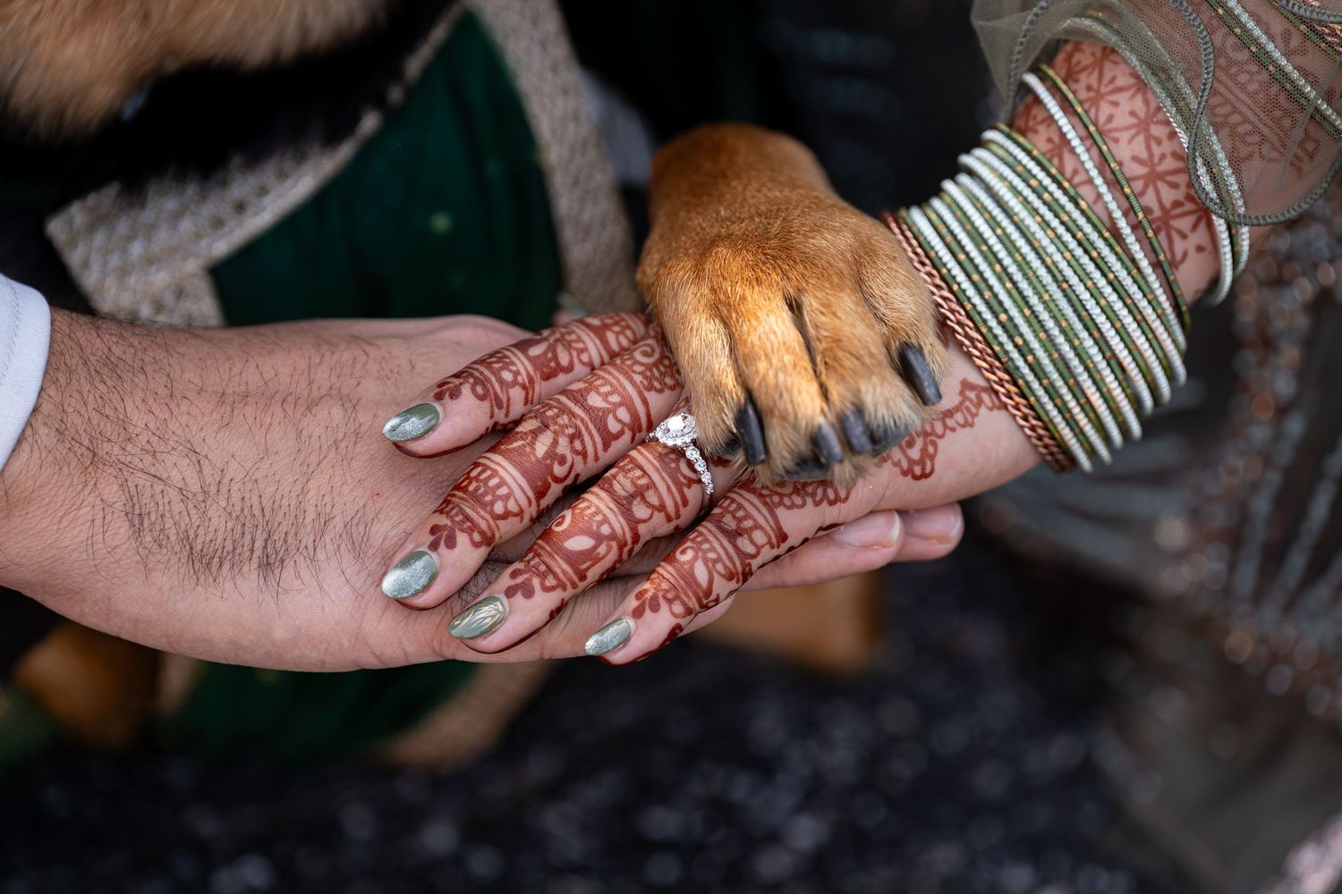 Detailed henna designs and bangles on hands during a traditional wedding ceremony.