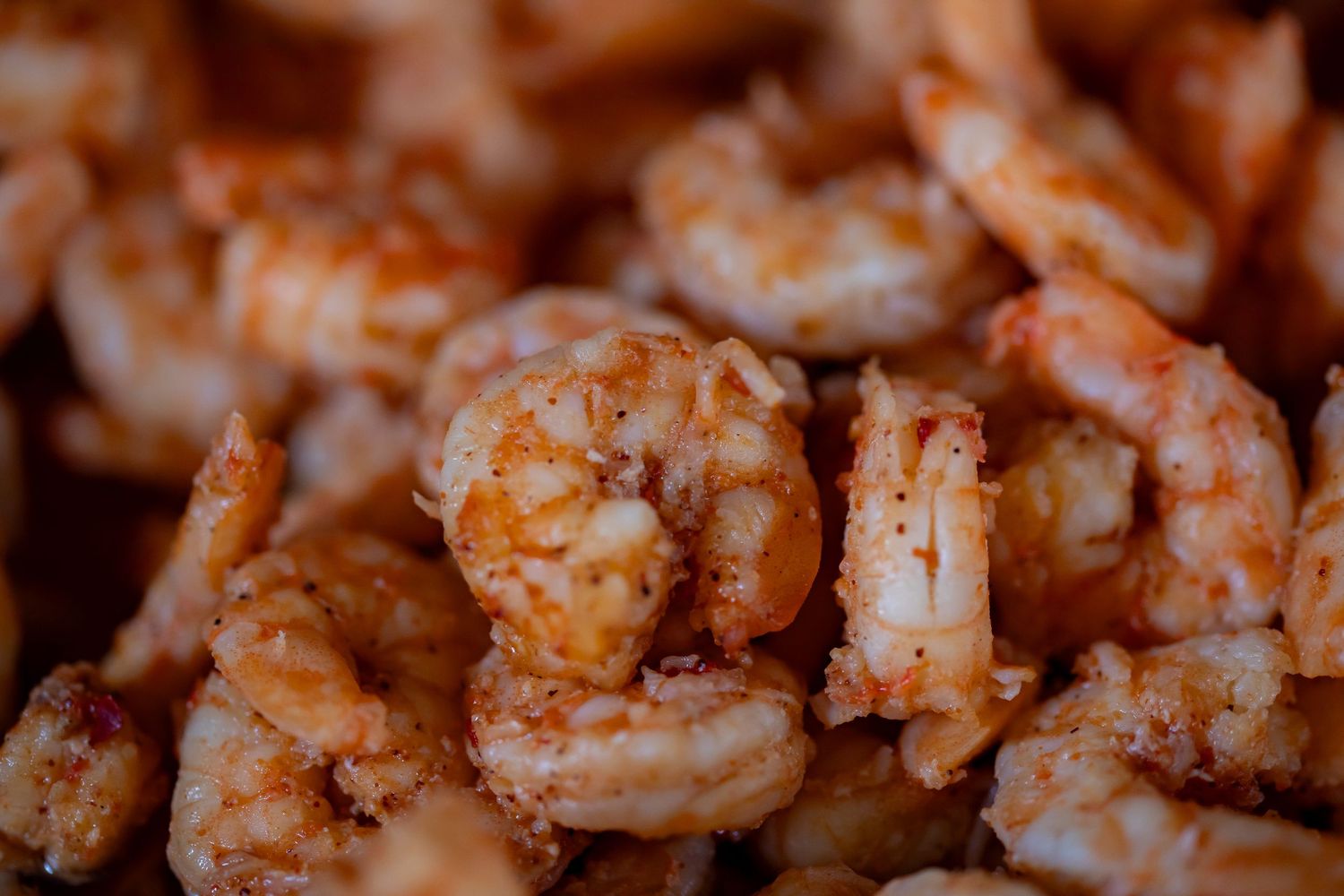 Close-up of seasoned grilled shrimp in warm lighting.