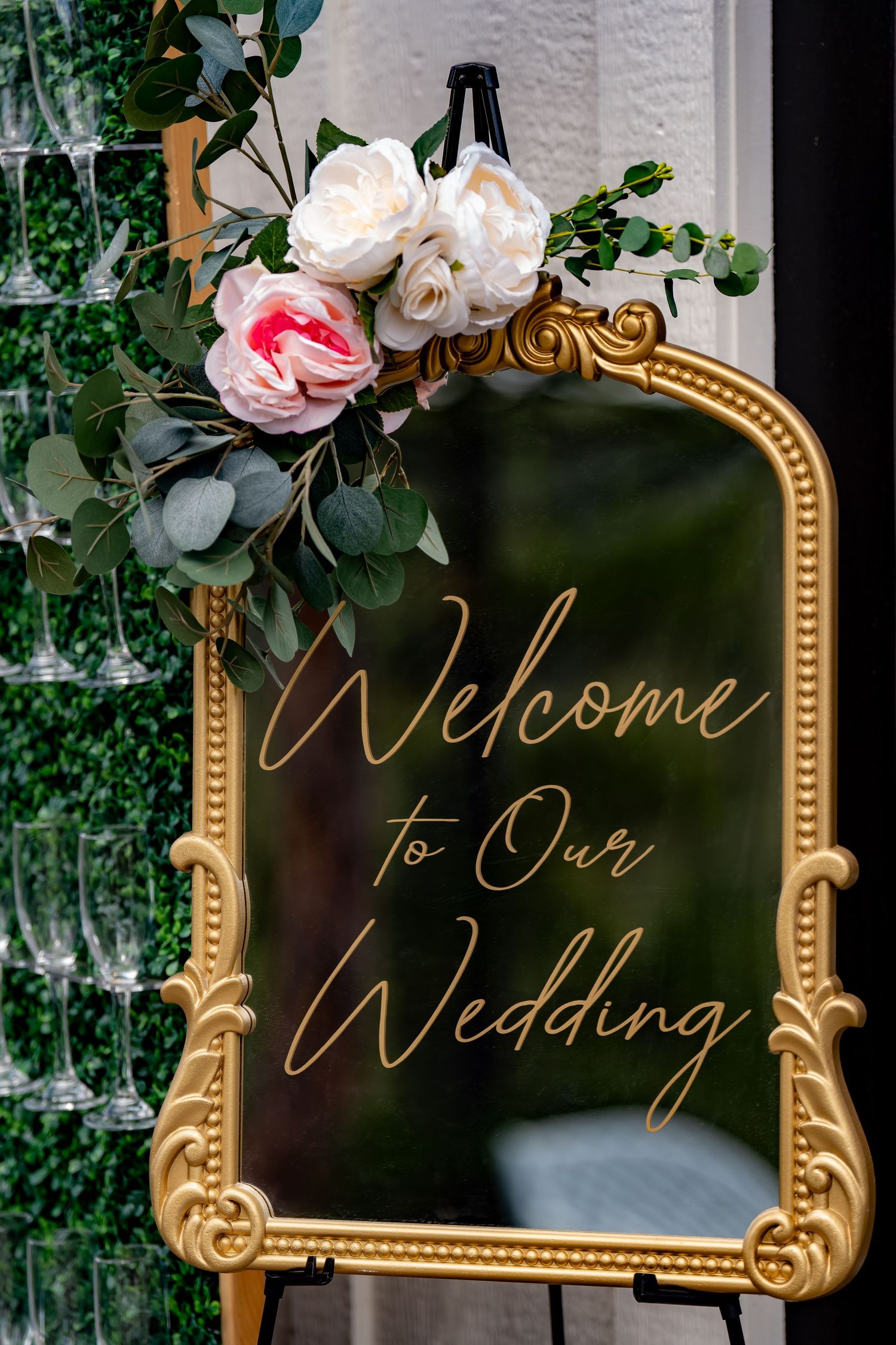 Ornate gold-framed mirror with 'Welcome to Our Wedding' calligraphy and floral decorations.