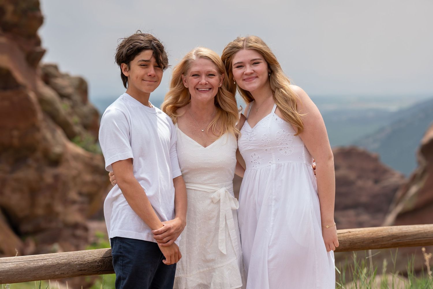 Family portrait session at scenic mountain overlook with rustic wooden fence.