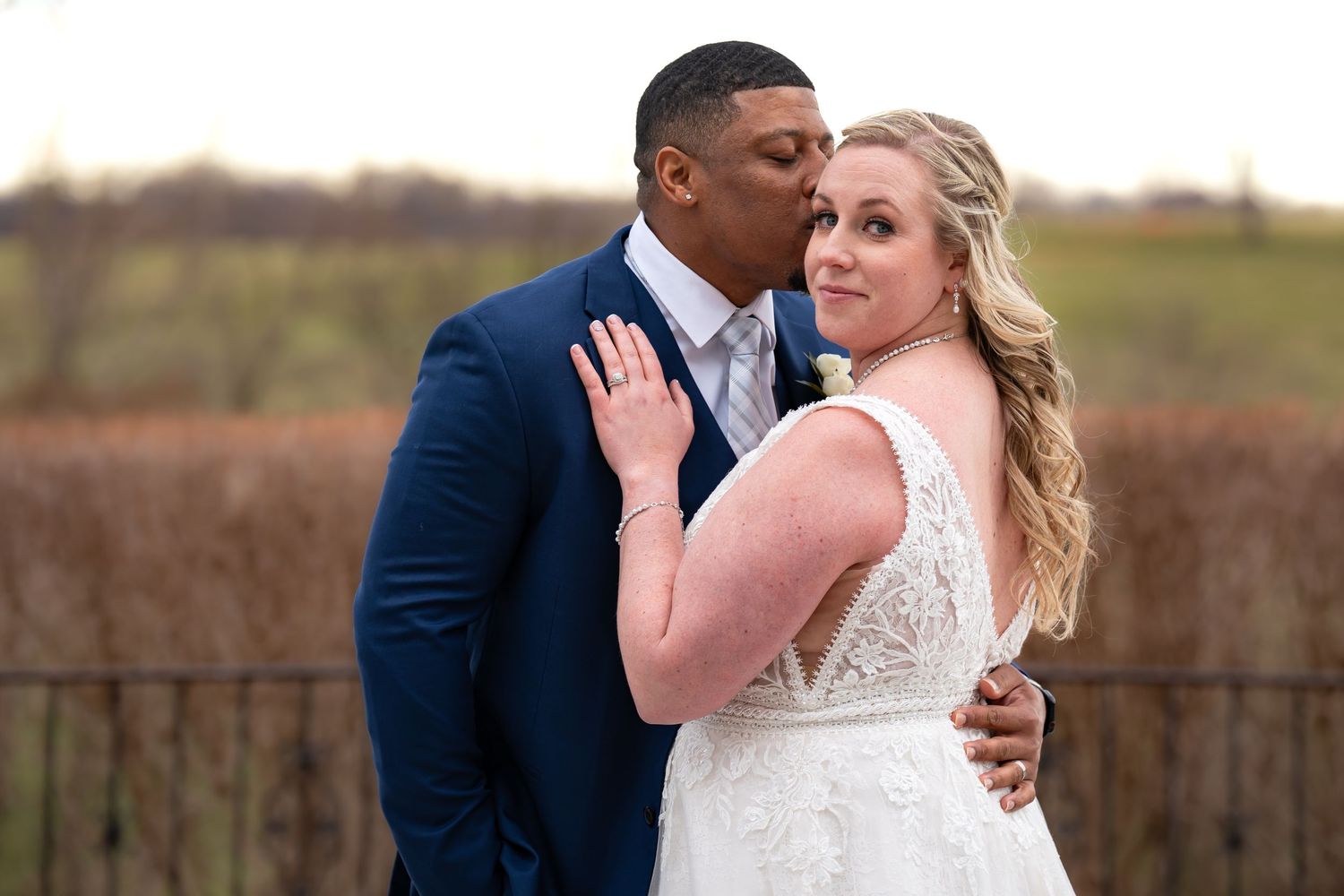 A romantic wedding portrait taken in front of a rustic wooden fence.