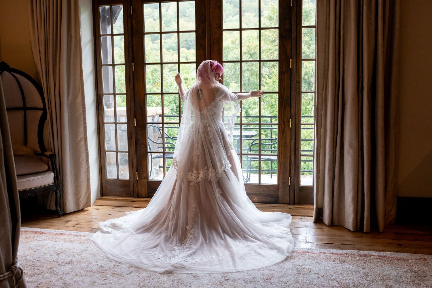 A wedding dress silhouette photographed against French doors in natural light.