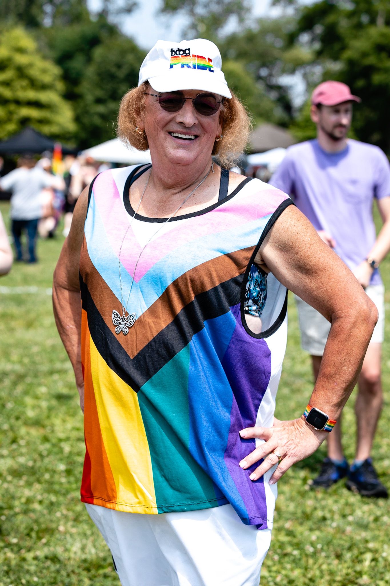 Person wearing colorful pride-themed athletic shirt at outdoor summer event.
