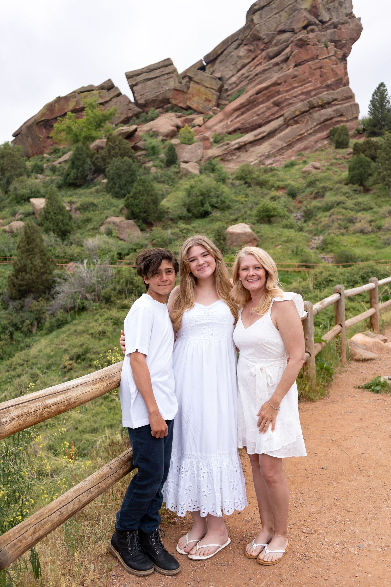 Family group dressed in white poses against red rock formations at a scenic overlook.