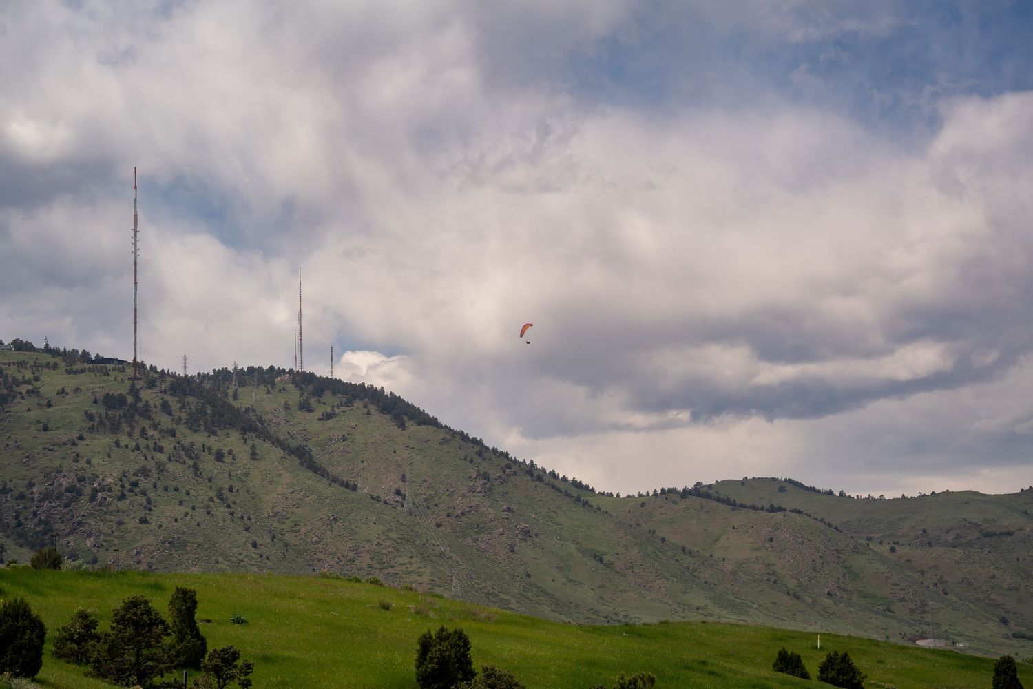 Rolling green hills and mountains under cloudy skies with transmission towers visible.