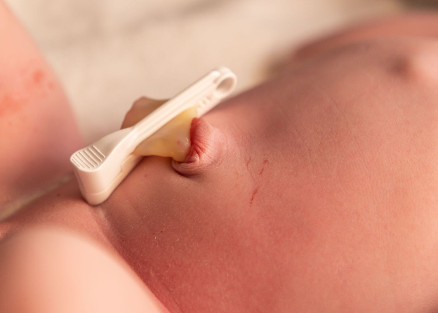 Close-up view of newborn baby's face being gently cleaned with soft cloth.