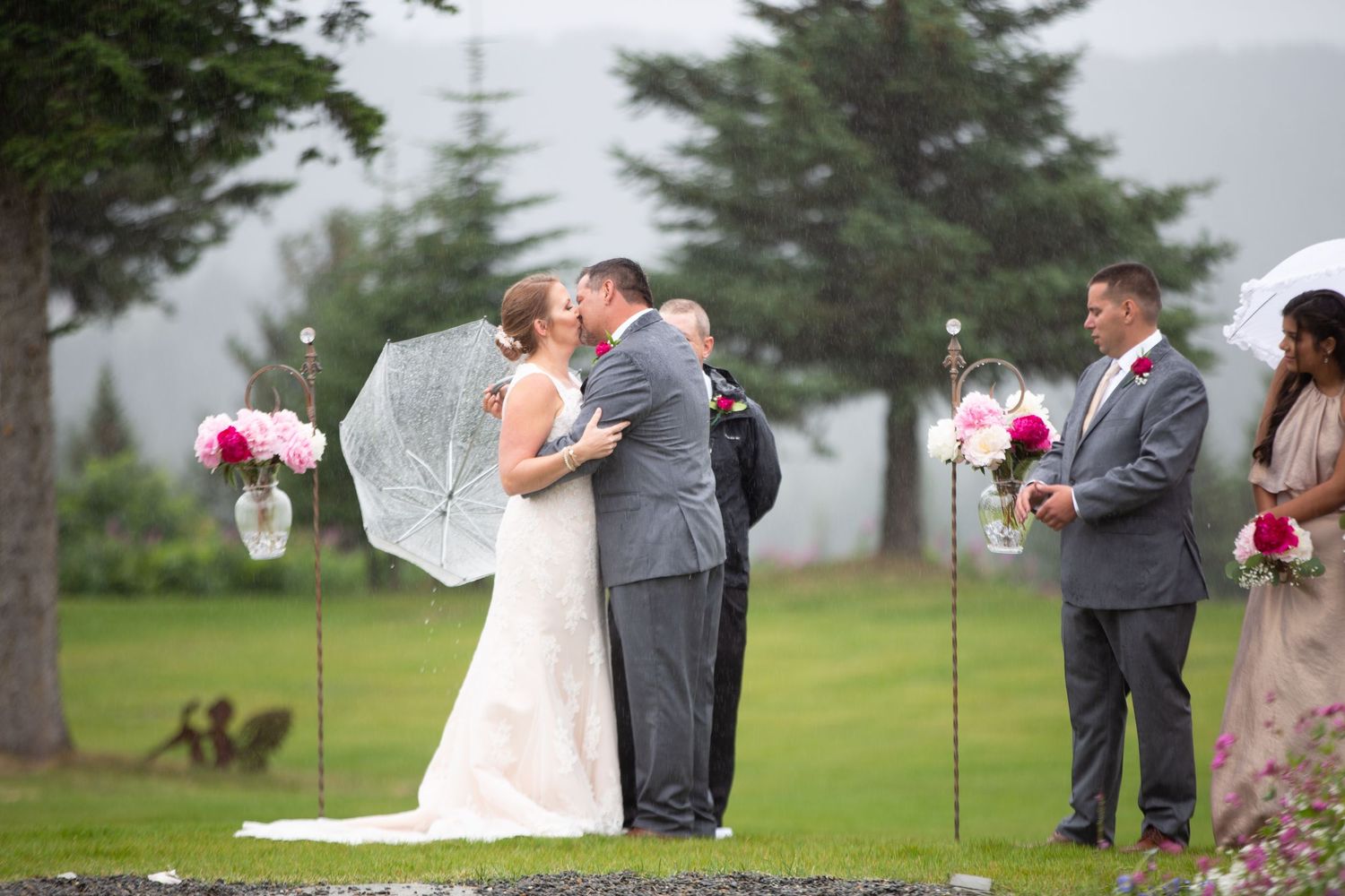 Wedding ceremony takes place on a misty lawn with evergreen trees in the background.