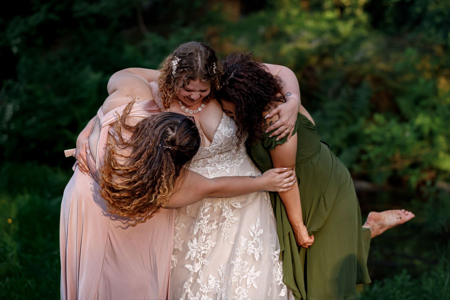 Wedding party members share emotional moments and hugs outdoors.