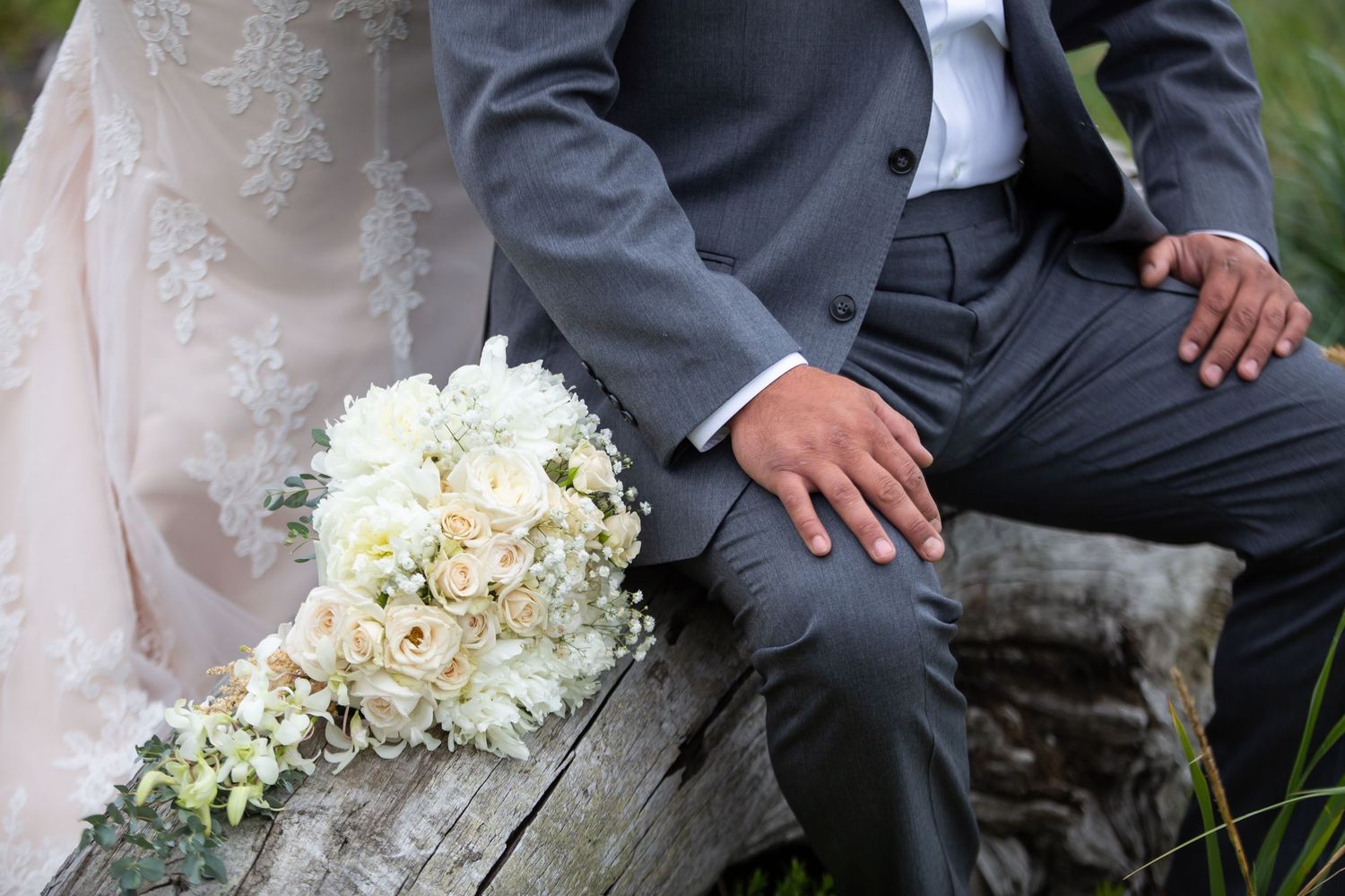 A close-up of a wedding bouquet with white roses next to formal attire.