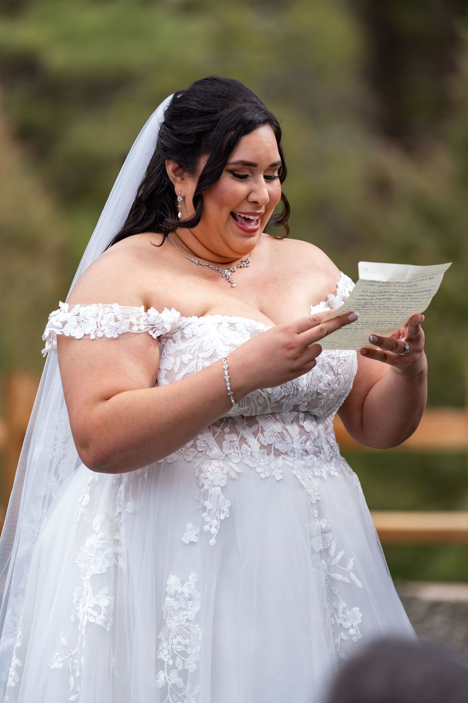 Emotional moment during wedding ceremony as couple reads from papers outdoors.