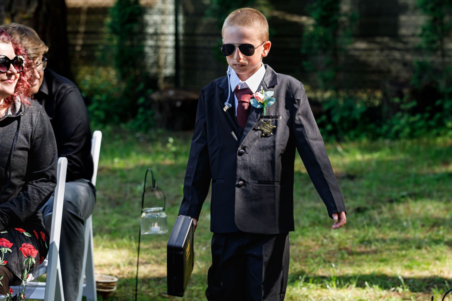 Wedding guests in formal attire gathering outdoors for photographs.