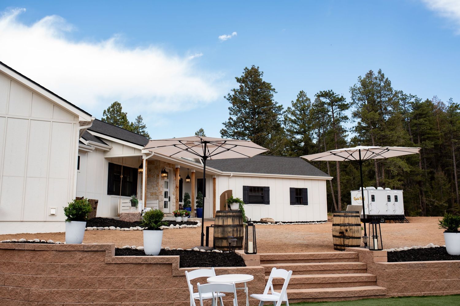 Outdoor wedding venue with white walls, wooden deck, and patio furniture on multiple levels.