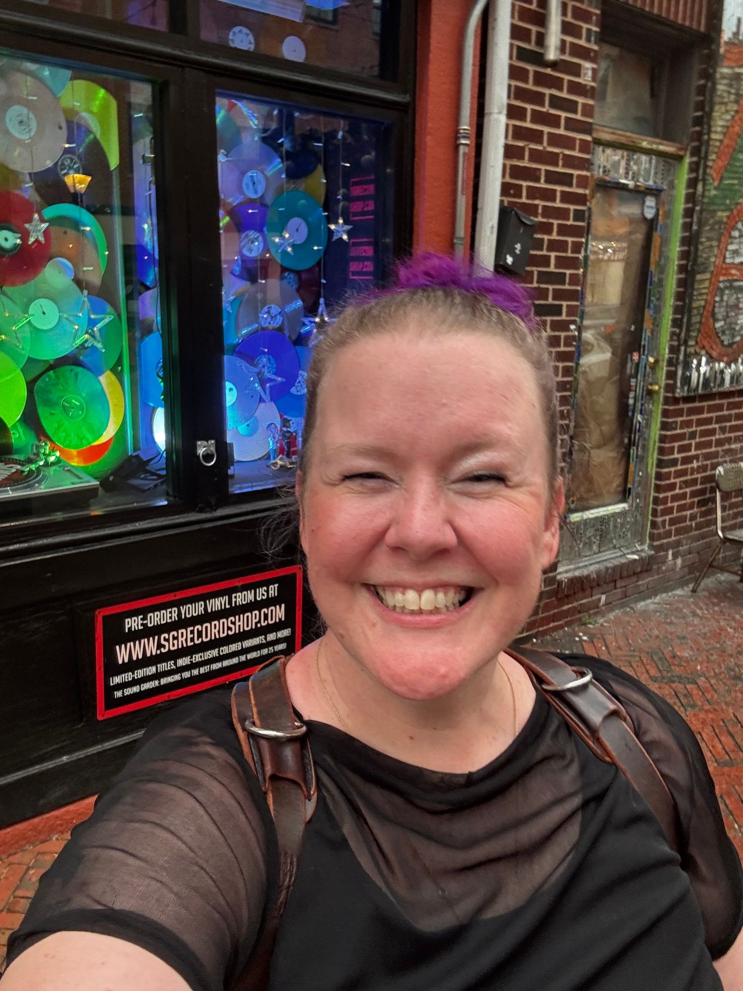 Storefront with vibrant painted window displays and brick facade at dusk.
