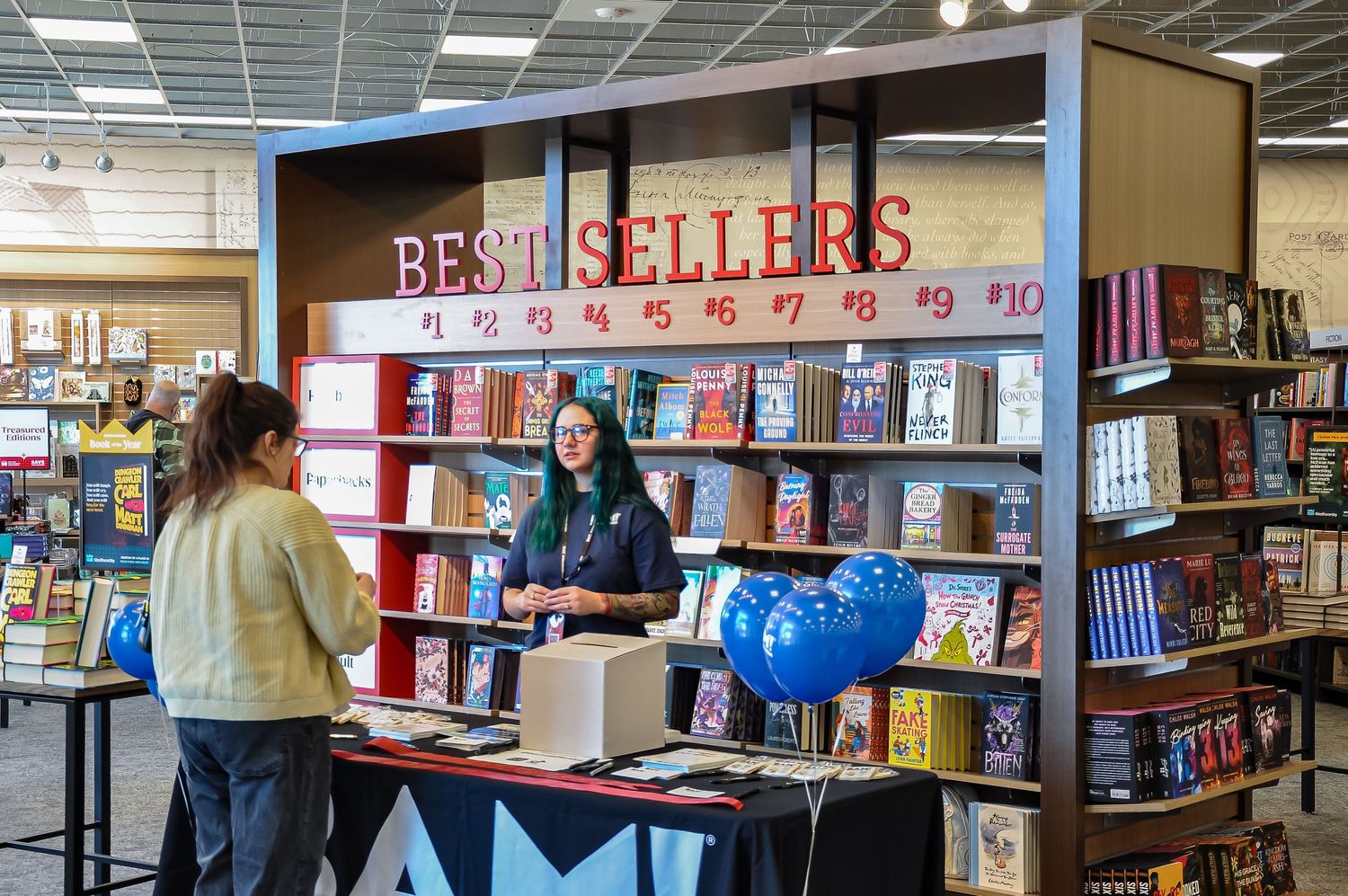 Bestsellers section in bookstore with display shelves and service counter.