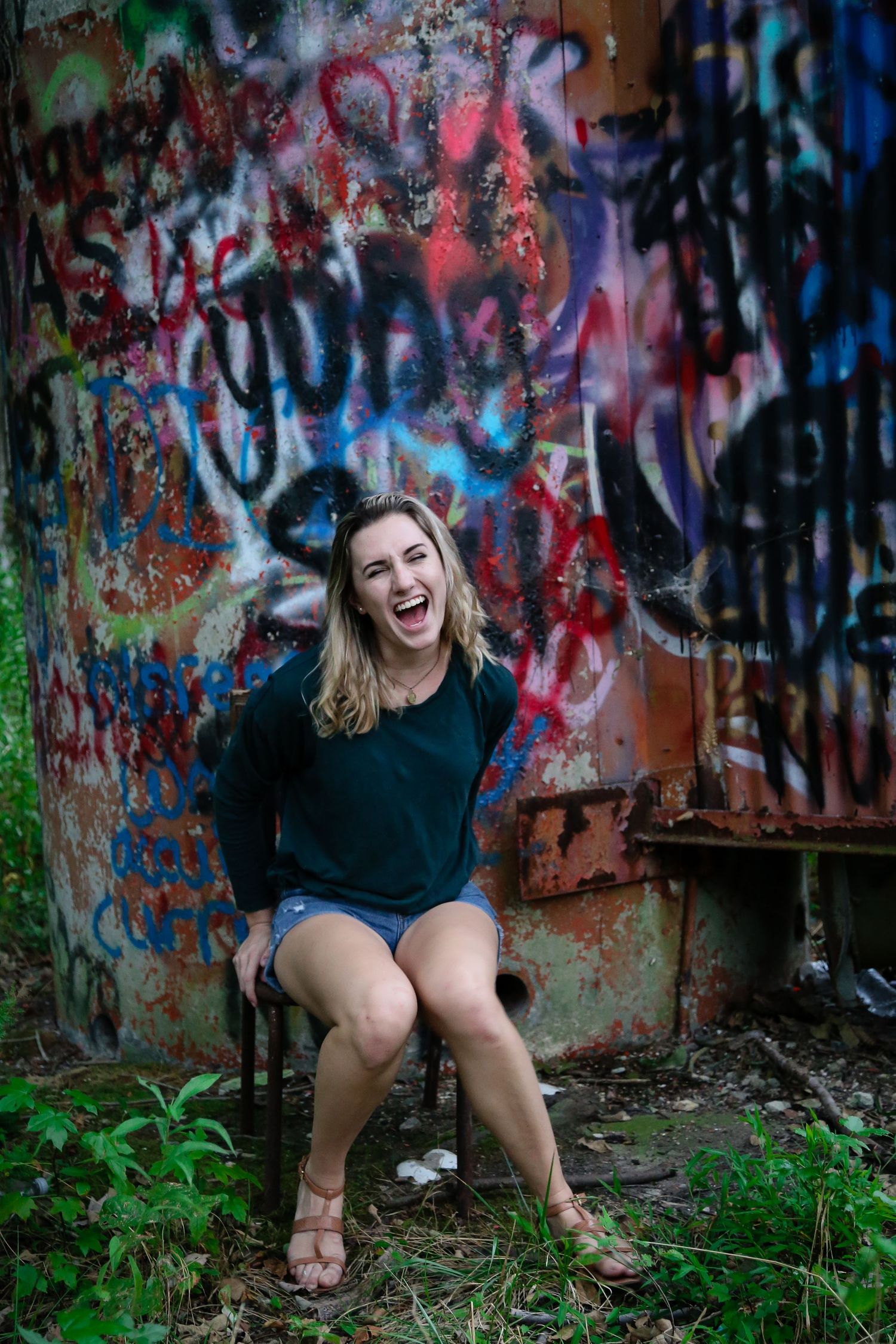 Urban photoshoot setting with vibrant graffiti walls and overgrown vegetation.