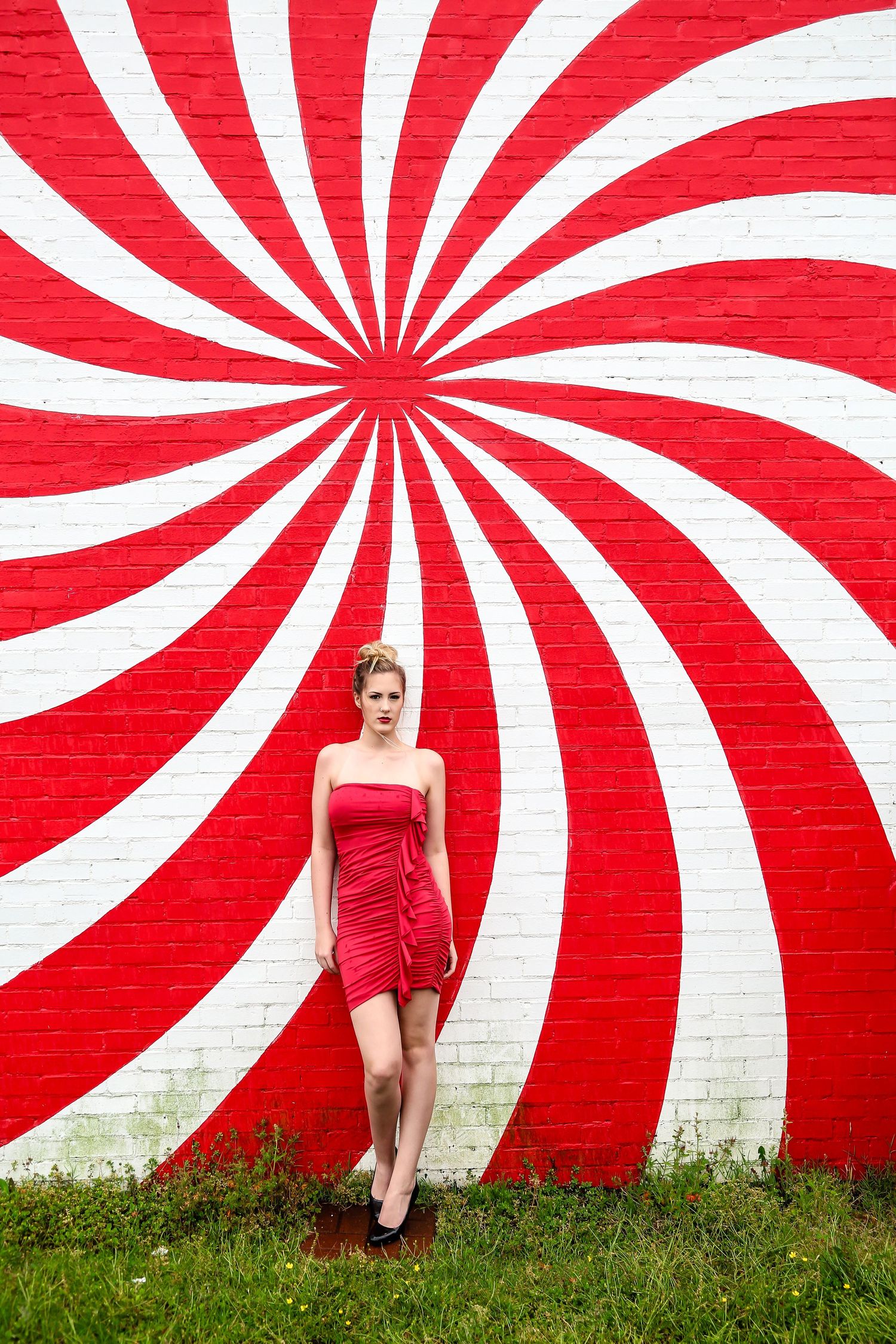 Striking red and white spiral wall creates dramatic backdrop for fashion photography.