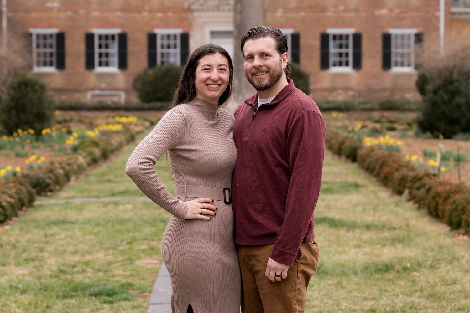 Maternity photos taken at historic location with brick buildings and garden setting.