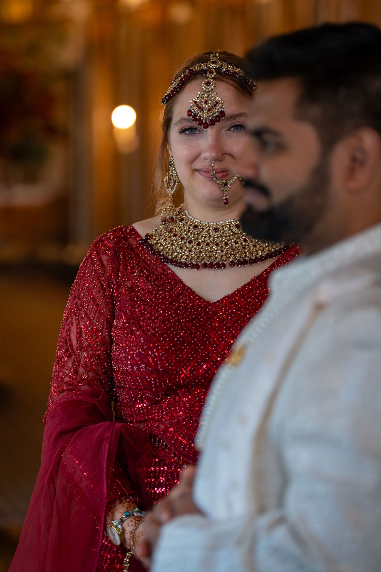 Traditional wedding attire featuring red beaded dress and ornate gold jewelry.