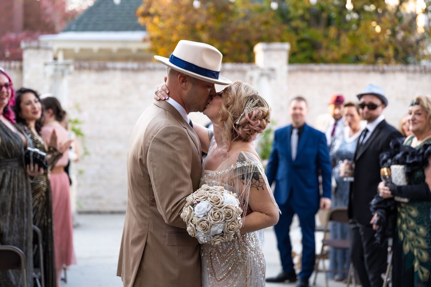Wedding couple poses against a brick wall during an outdoor celebration.