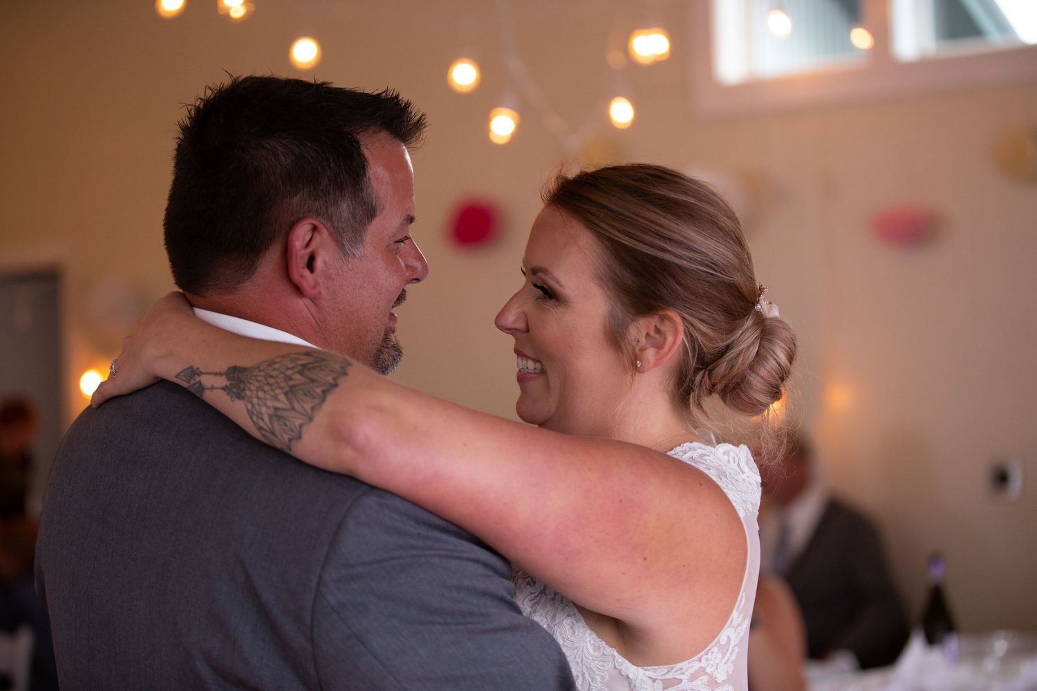 Intimate dance moment captured between couple at wedding reception with string lights overhead.