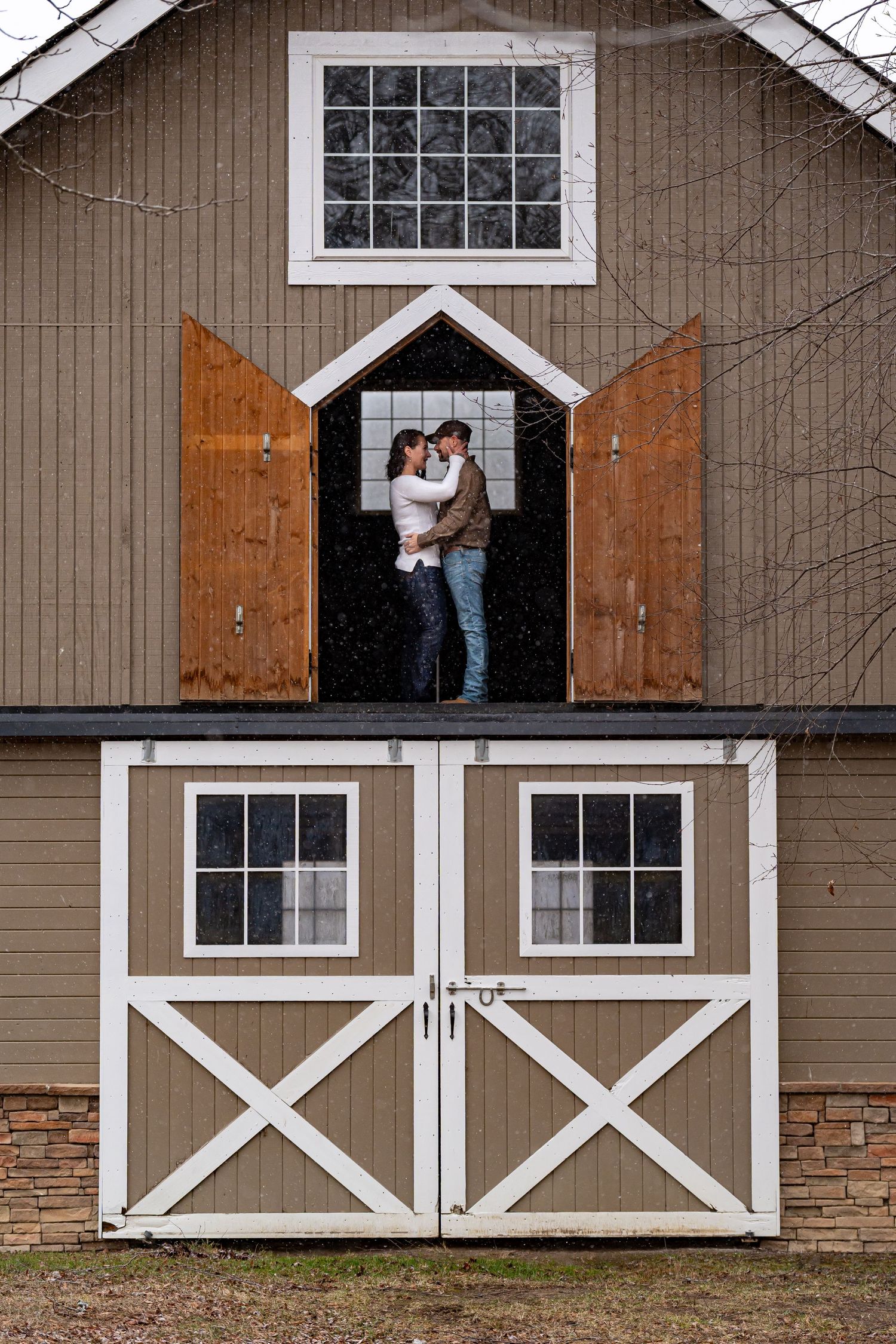 Rustic barn with white trim and wooden doors creates charming wedding venue backdrop.