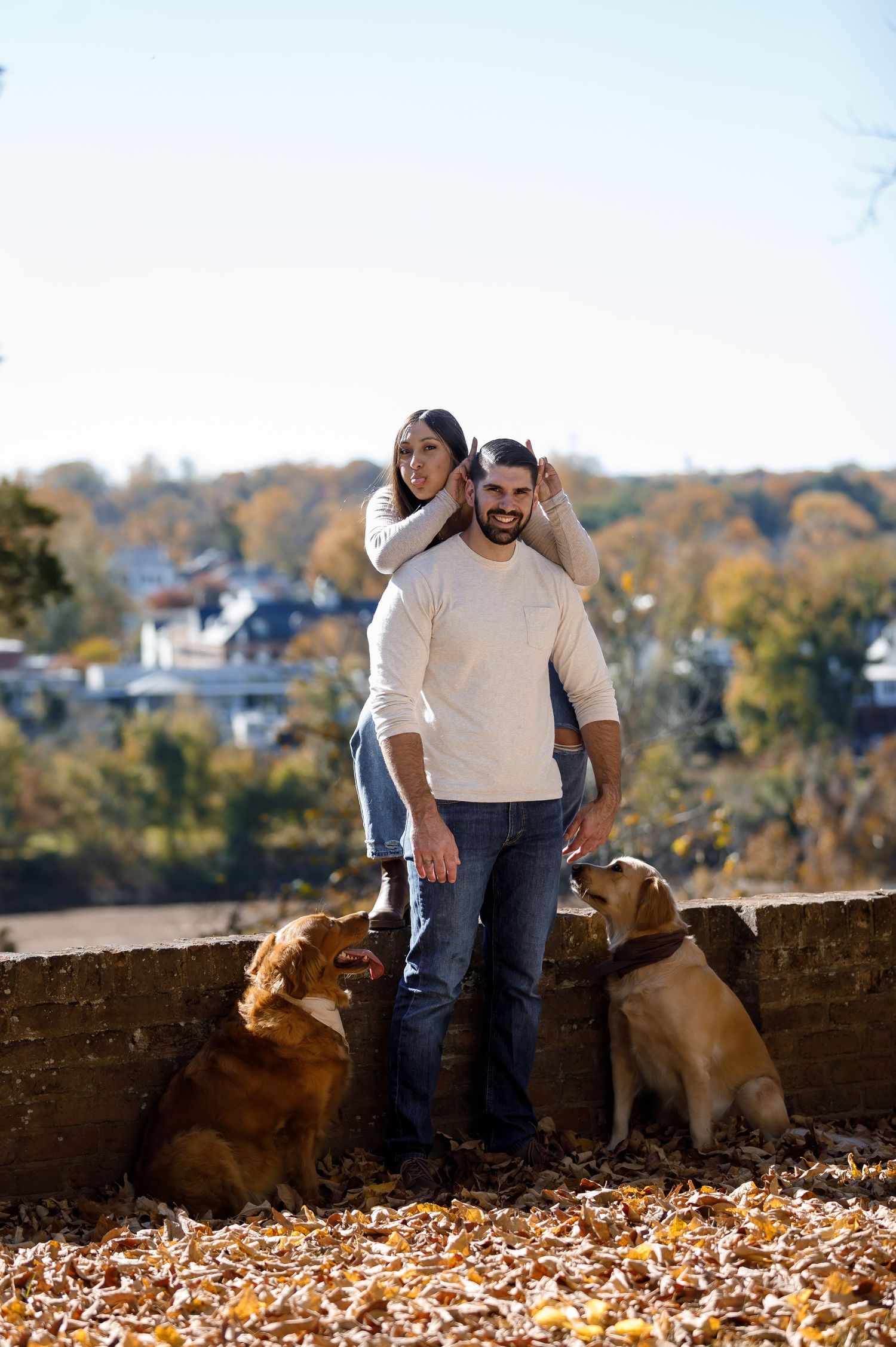 Couple and their dogs enjoying a fall afternoon against urban backdrop.