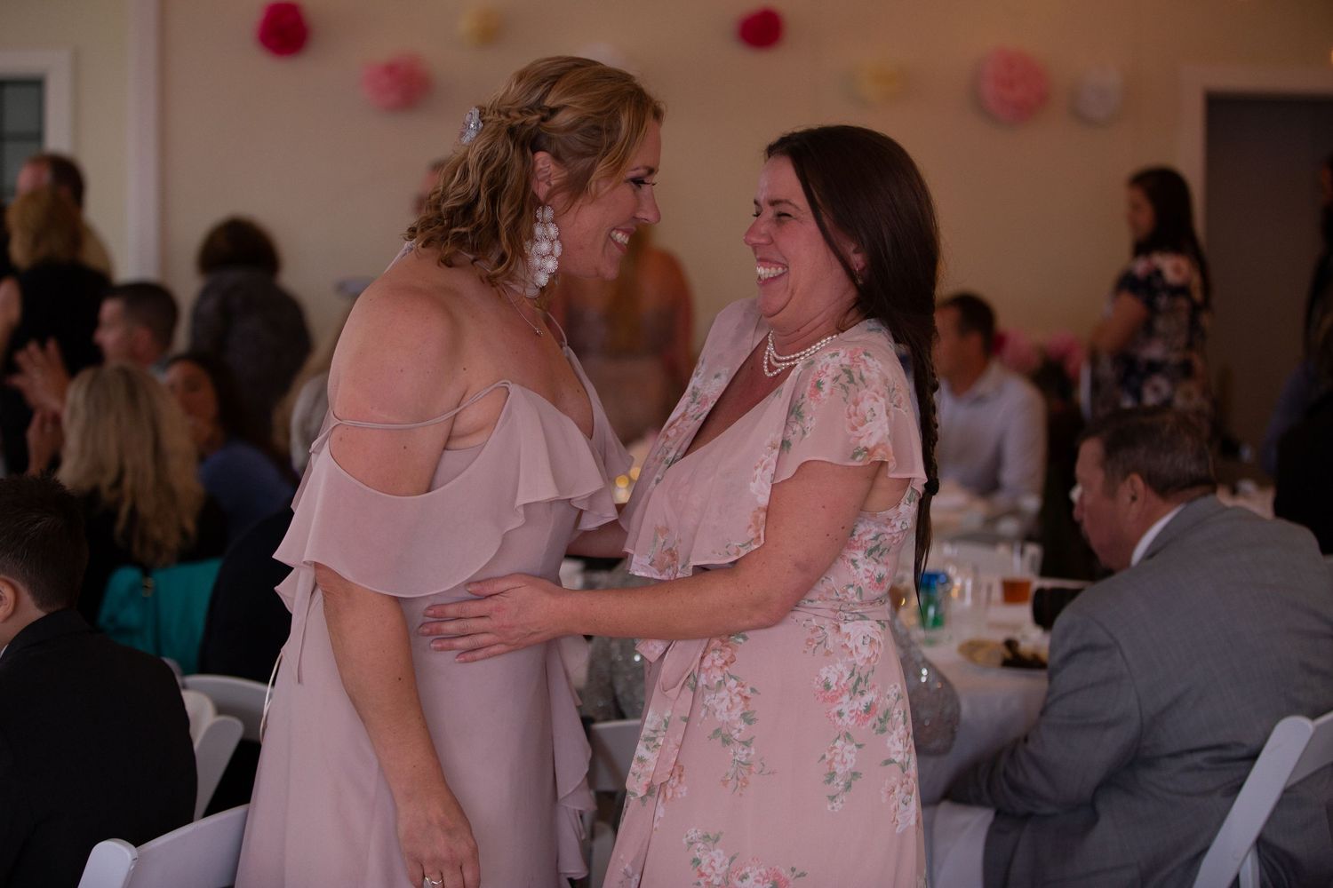 People dance and celebrate at a joyful wedding reception with pink decorations in the background.