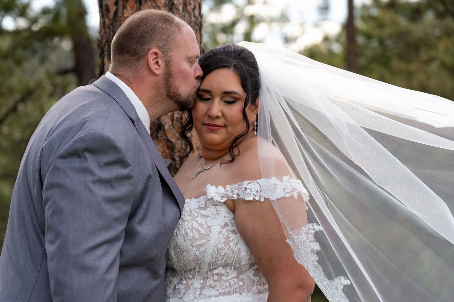Romantic outdoor wedding portraits with flowing veil in a forest setting.