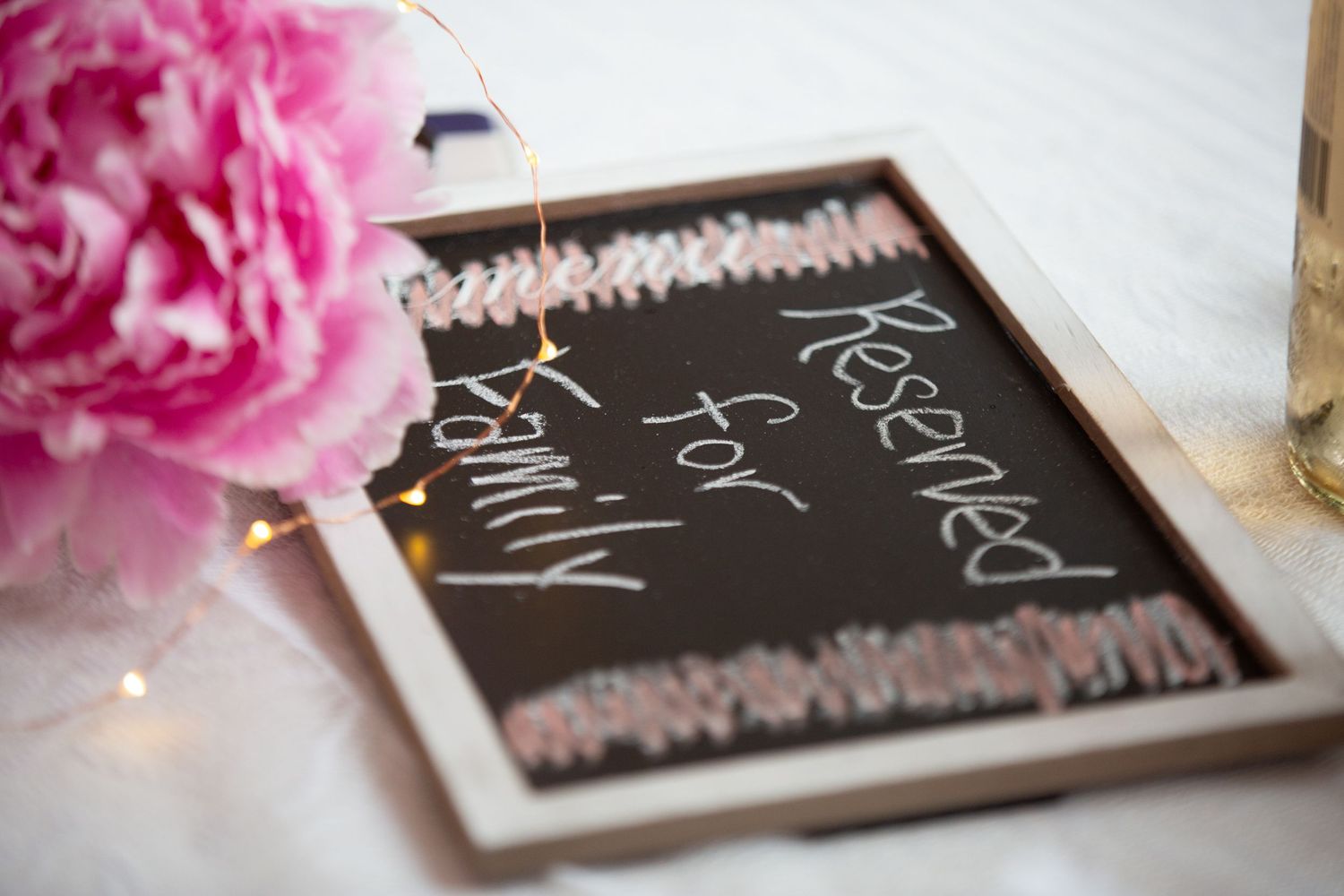 A chalkboard sign surrounded by pink flowers creates a decorative display.